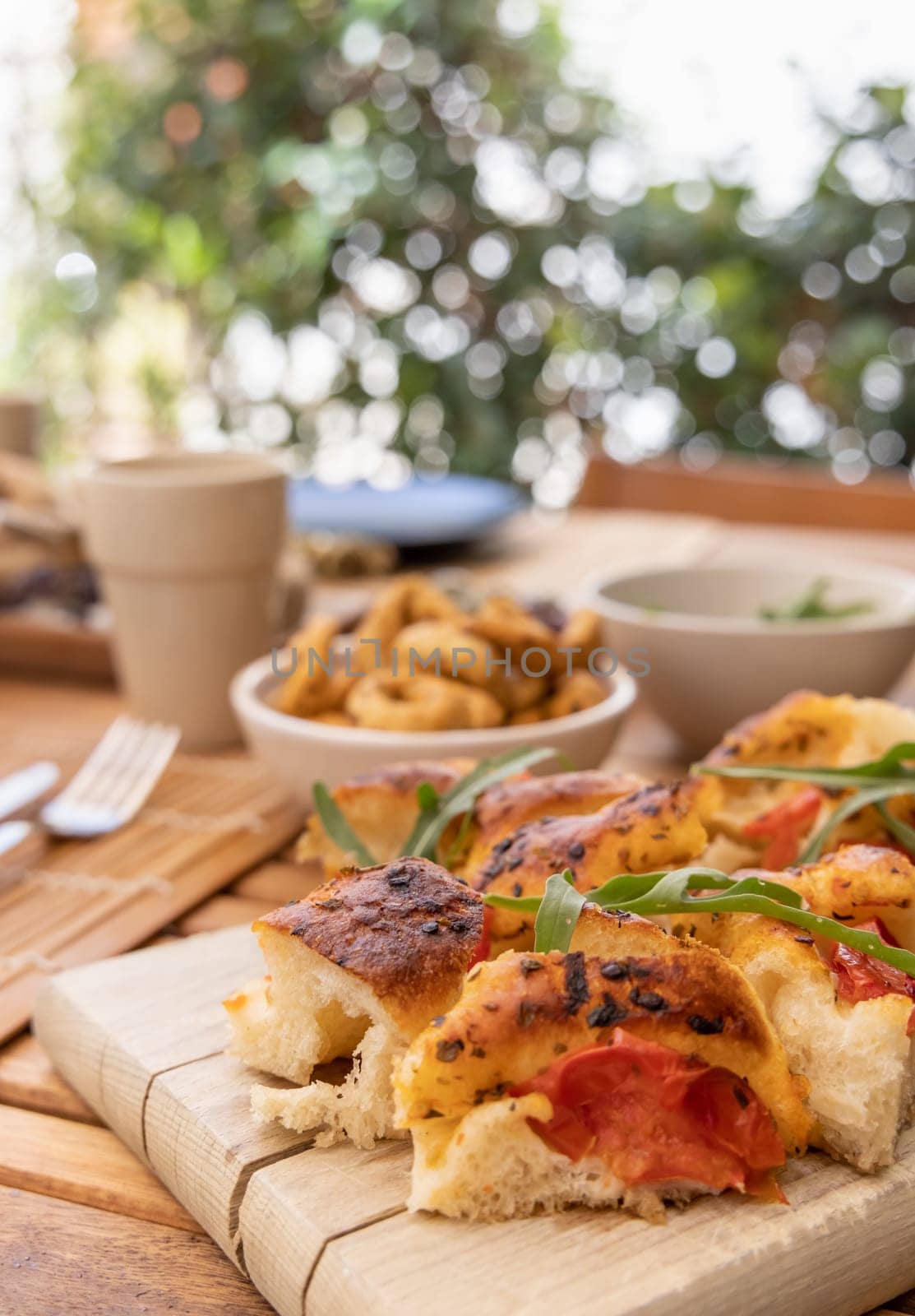 Italian summer appetizer focaccia with cherry tomatoes and rucola served outdoor with glasses of red wine. Tipical Apulian Dried bread, made in Salento. Local cousine. Vegetarian food