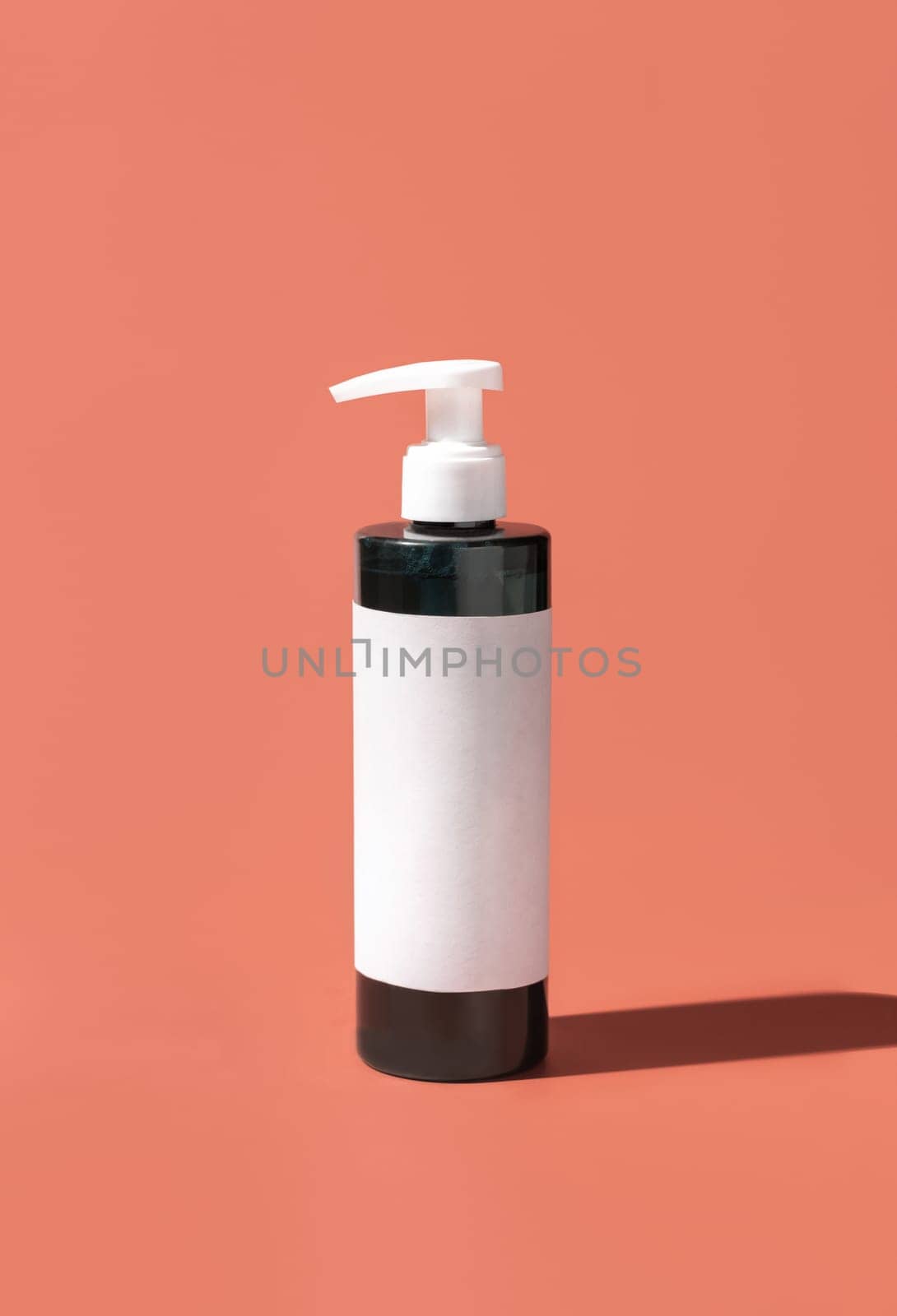 Cosmetic One pump Plastic bottle with blank label on pink, hard shadows, close up, mockup. Skincare beauty product, facial cleaner or lotion. Natural cosmetics..
