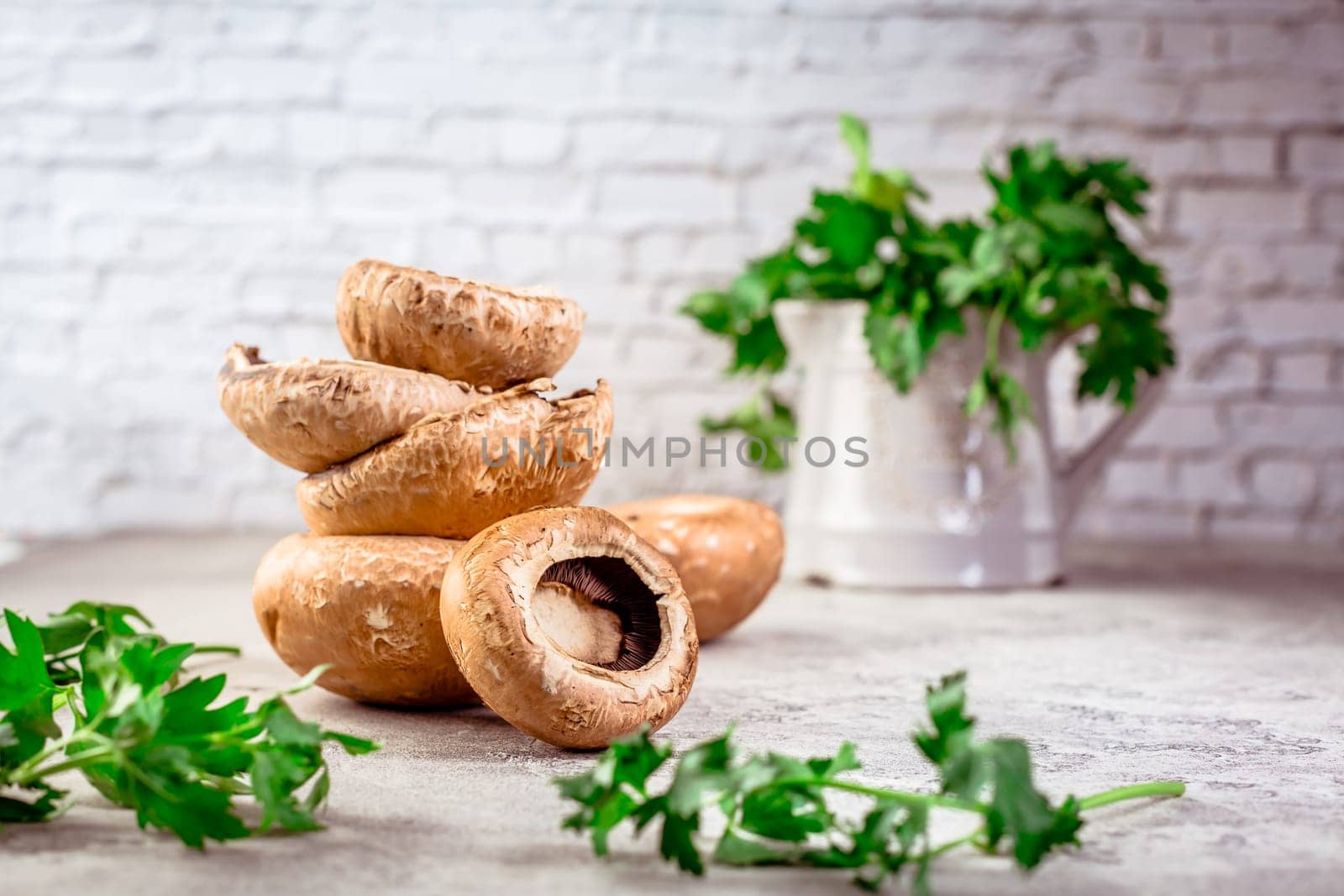 Raw portobello mushrooms with fresh parsley on kitchen table prepared for cooking