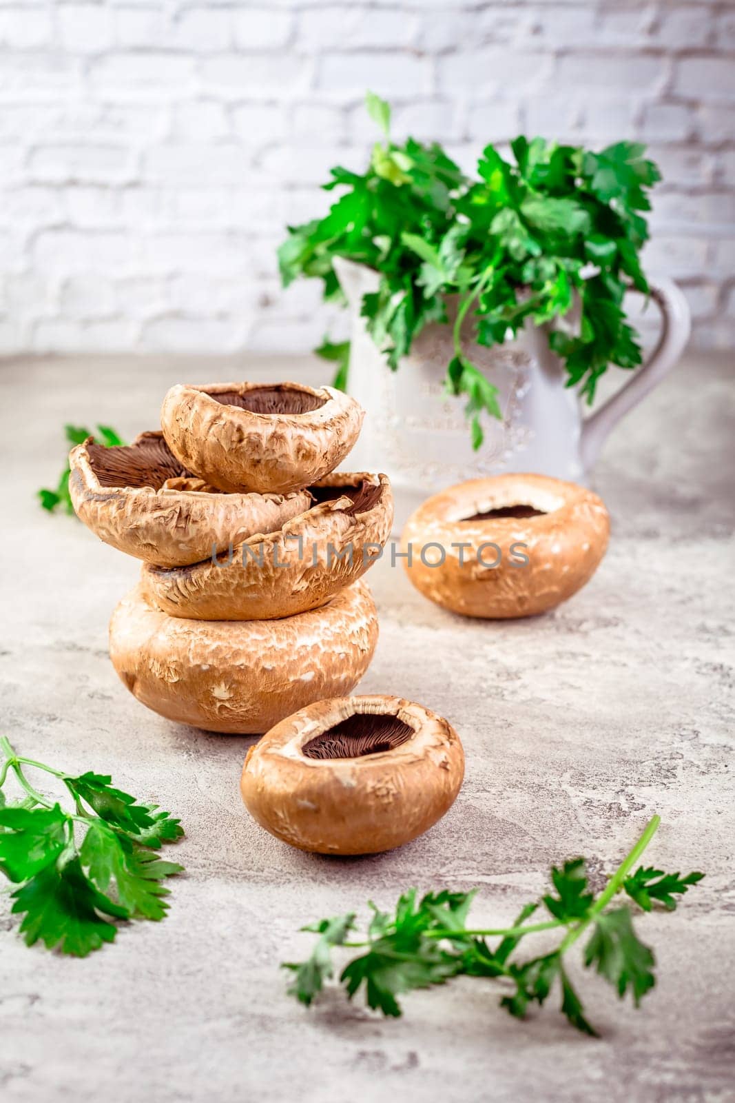 Raw portobello mushrooms with fresh parsley on kitchen table prepared for cooking
