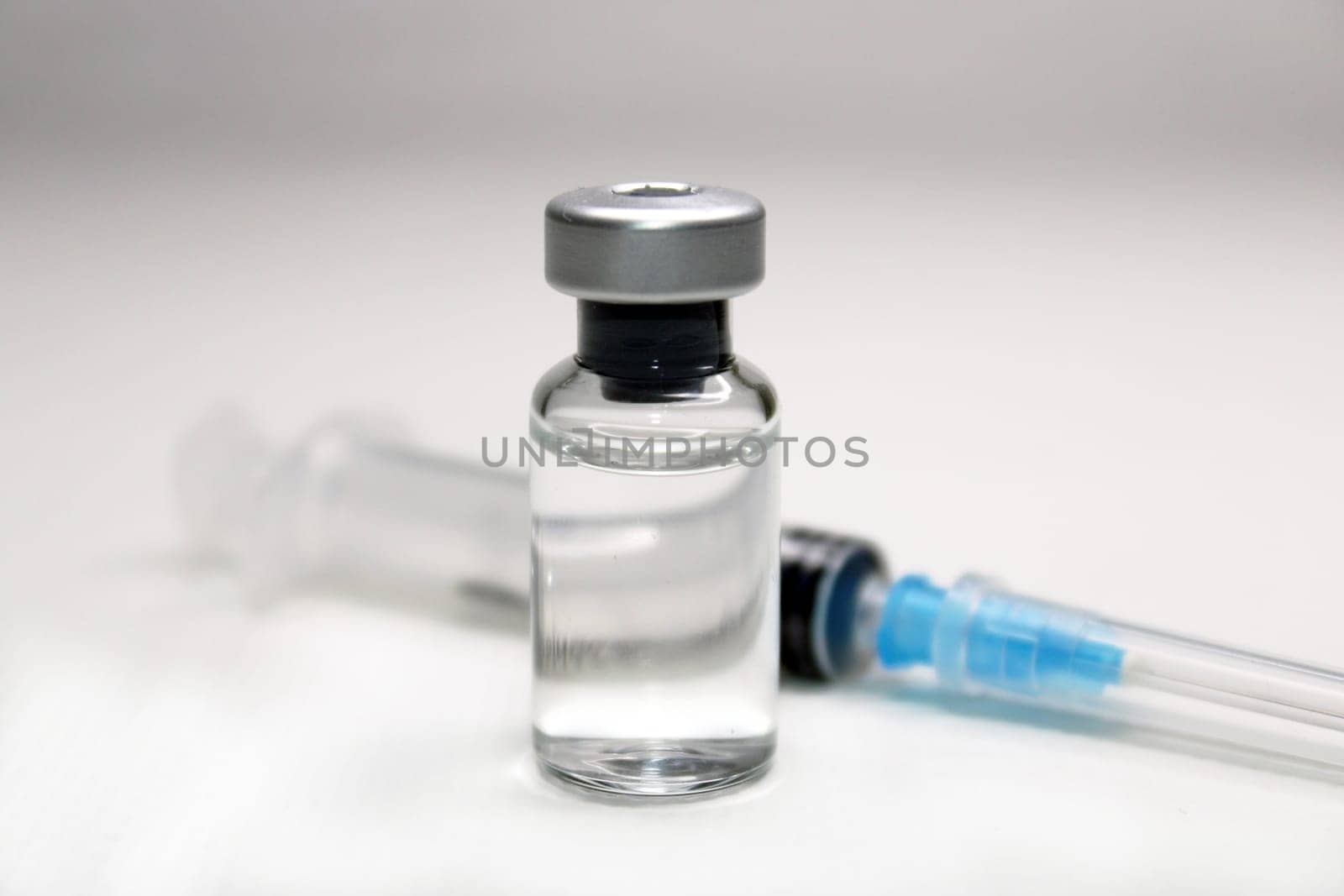 Syringe and a bottle of medicine close-up on a light background. Blurred background.