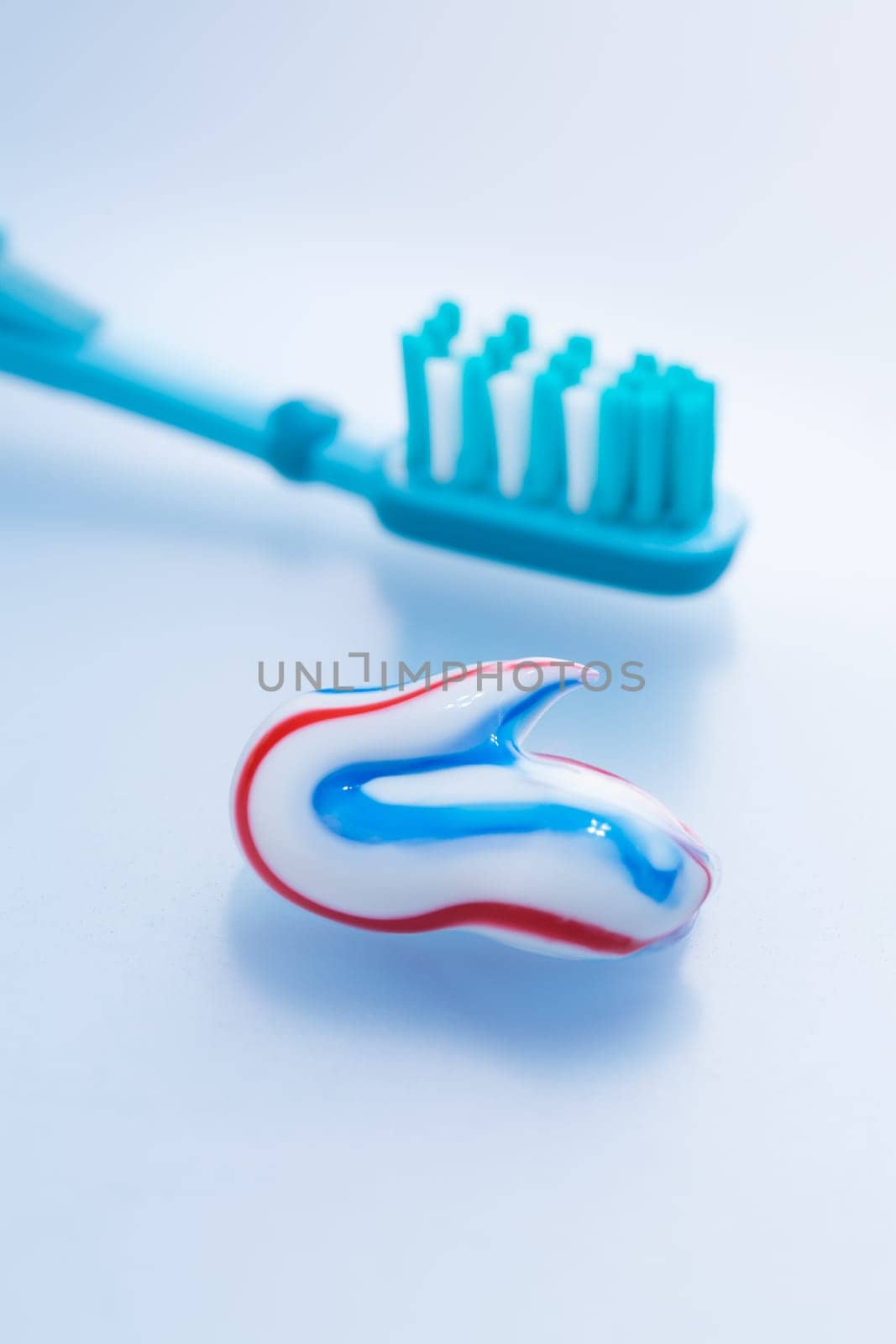Colorful toothpaste and toothbrush on blue background, concept of dental care and hygiene