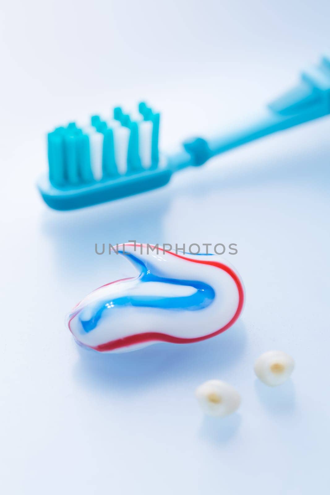 Colorful toothpaste and toothbrush with primary teeth on blue background, concept of dental care and hygiene