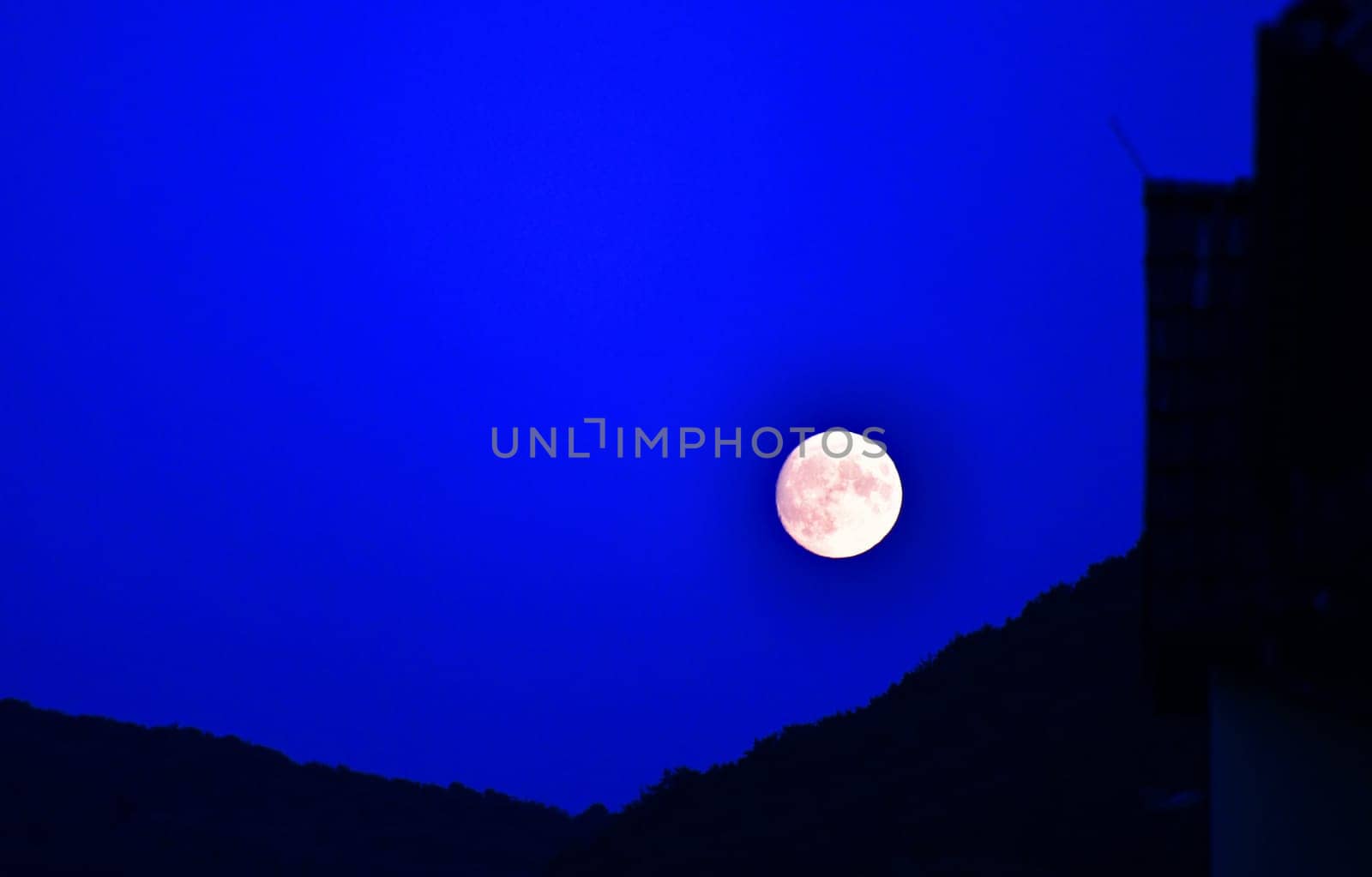 The moon rises behind a mountain