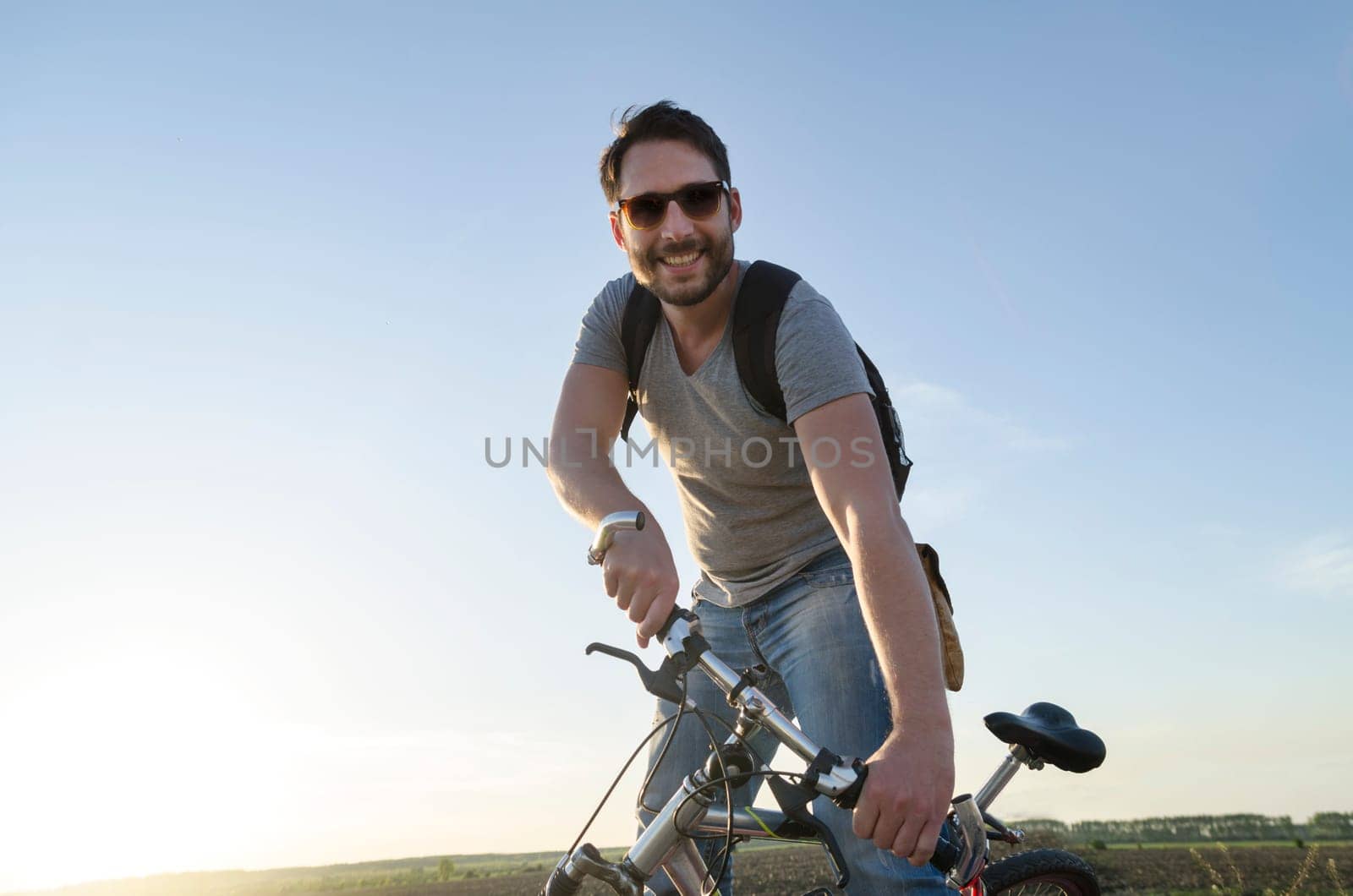 Man riding a bicycle and having outdoor fun. Summer holiday backpack adventure traveler.