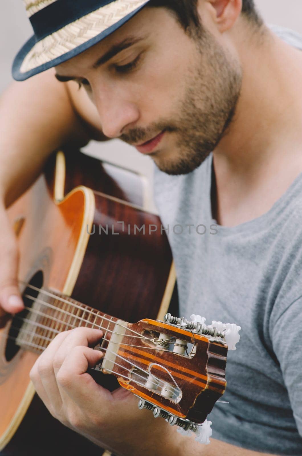 Young man with hipster hat playing the guitar and having fun on the street.