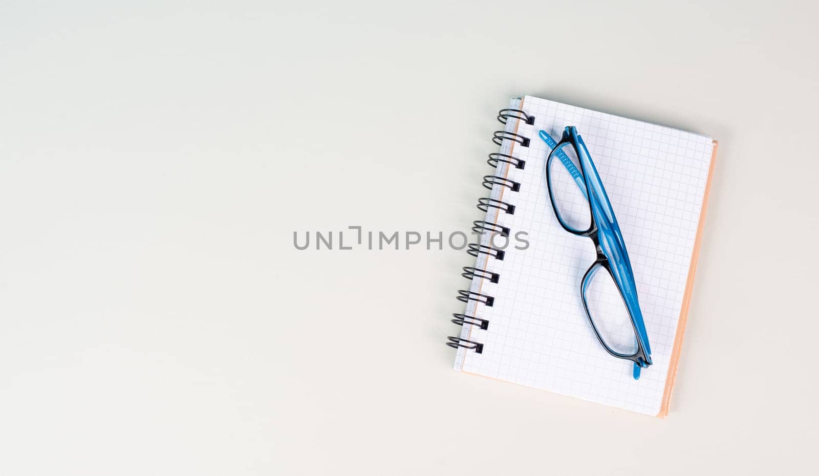 Empty notebook and eyeglasses on a gray background, brainstorming for new ideas, writing a message, home office desk, template of a workspace, copy space for text