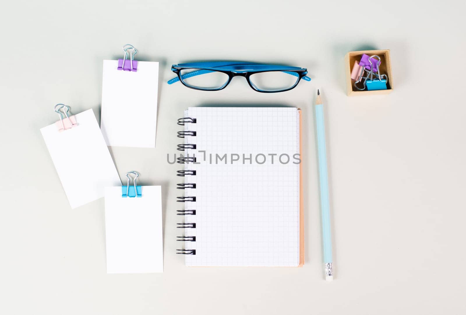 Blank notebook with a pen, paper and eyeglasses on a gray background, brainstorming for ideas, writing a message, workplace desk, home office