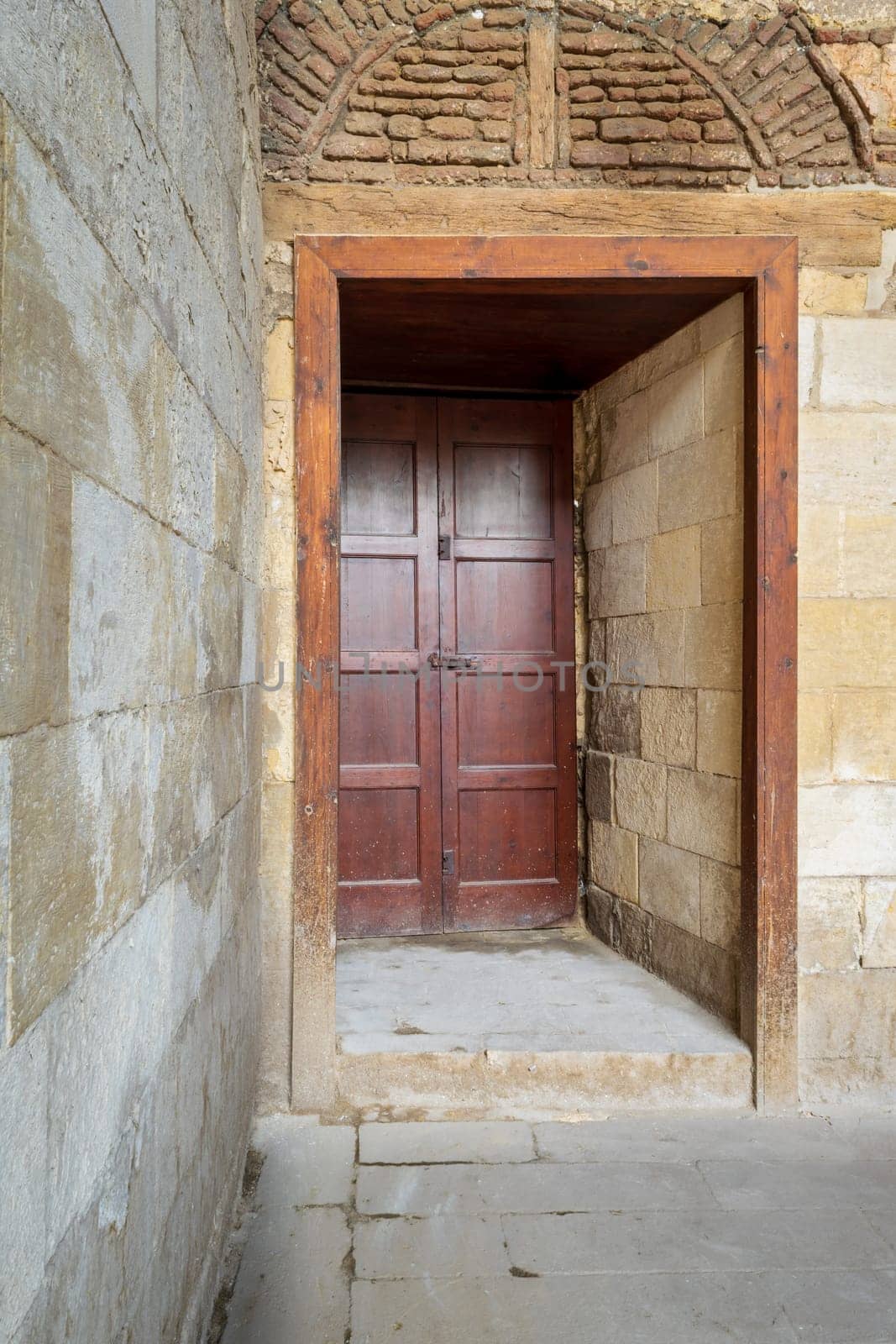 Recessed wooden aged engraved door and stone wall, Medieval Cairo, Egypt