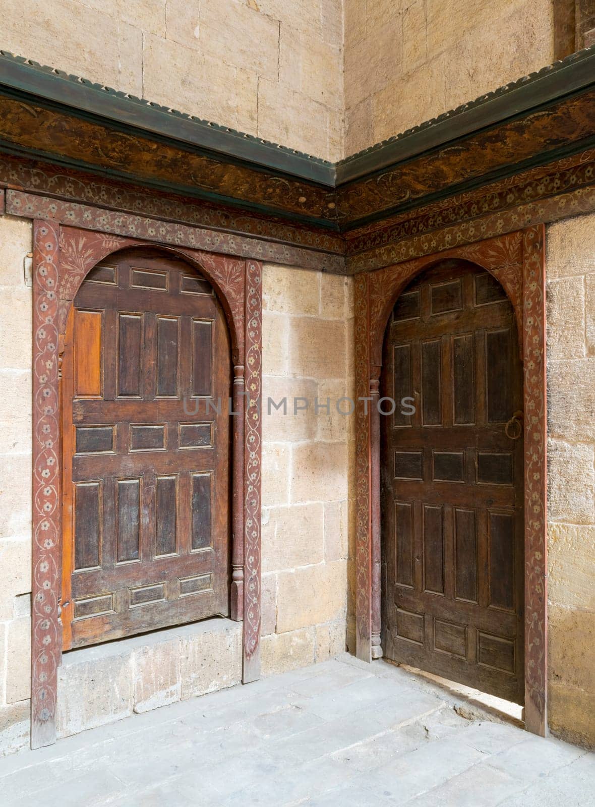 Two wooden aged ornate vaulted perpendicular doors on stone bricks walls, Medieval Cairo, Egypt