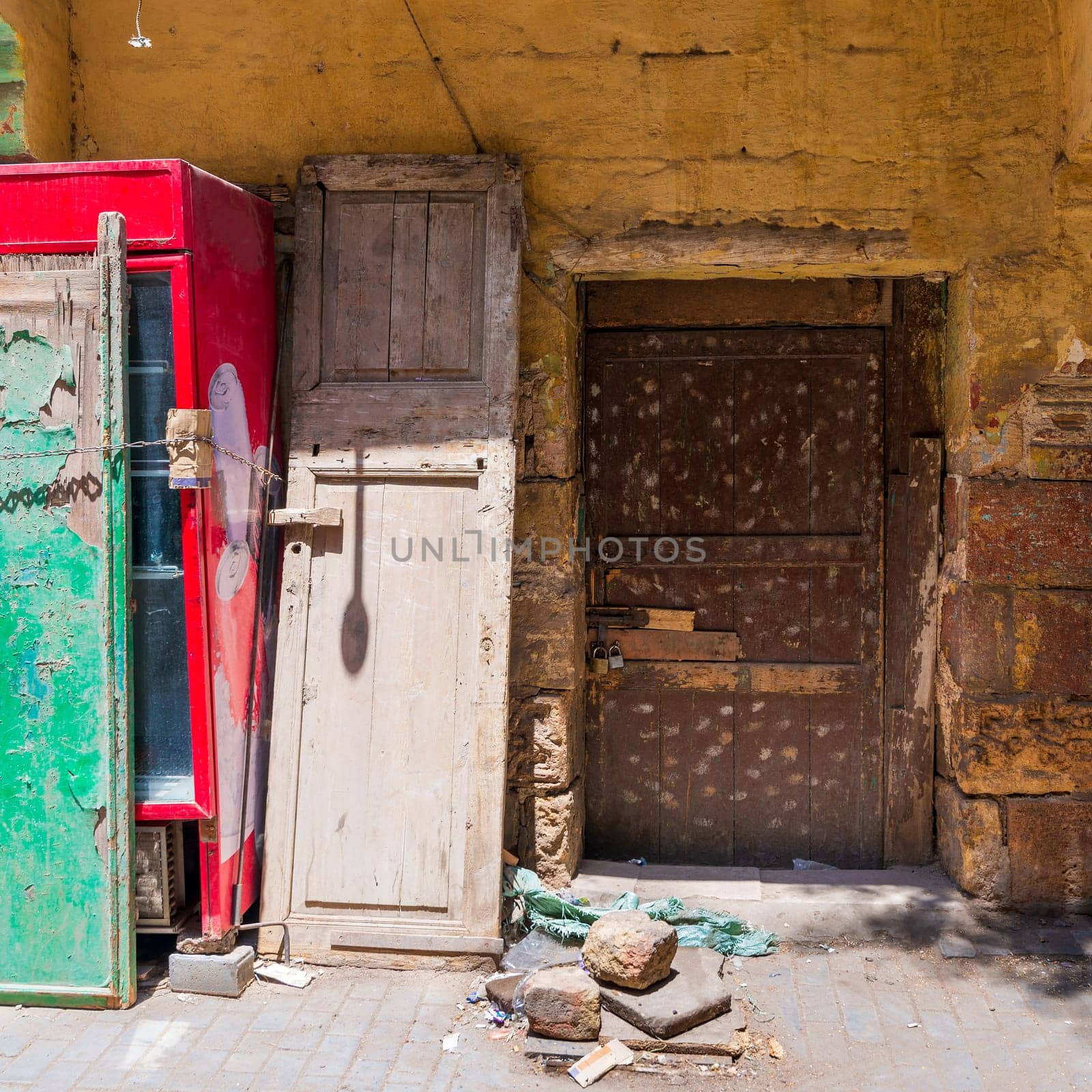 Broken wooden brown door on grunge stone bricks wall painted in orange in abandoned Darb El Labana district, Cairo, Egypt
