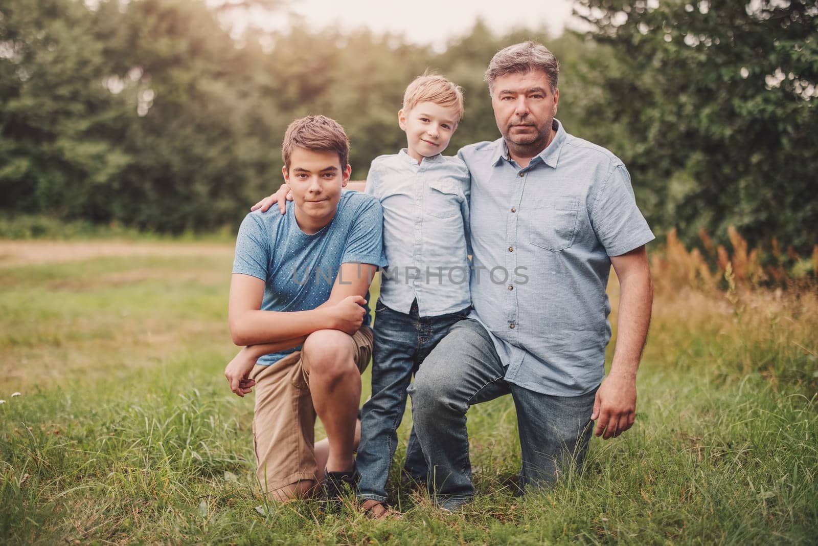 Father with his sons standing in the natural park. Concept of family relation and love.