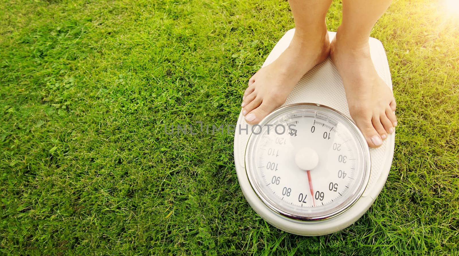 Woman standing on the white scales with bare feet in nature. Concept of the weight loss and healthy lifestyle.