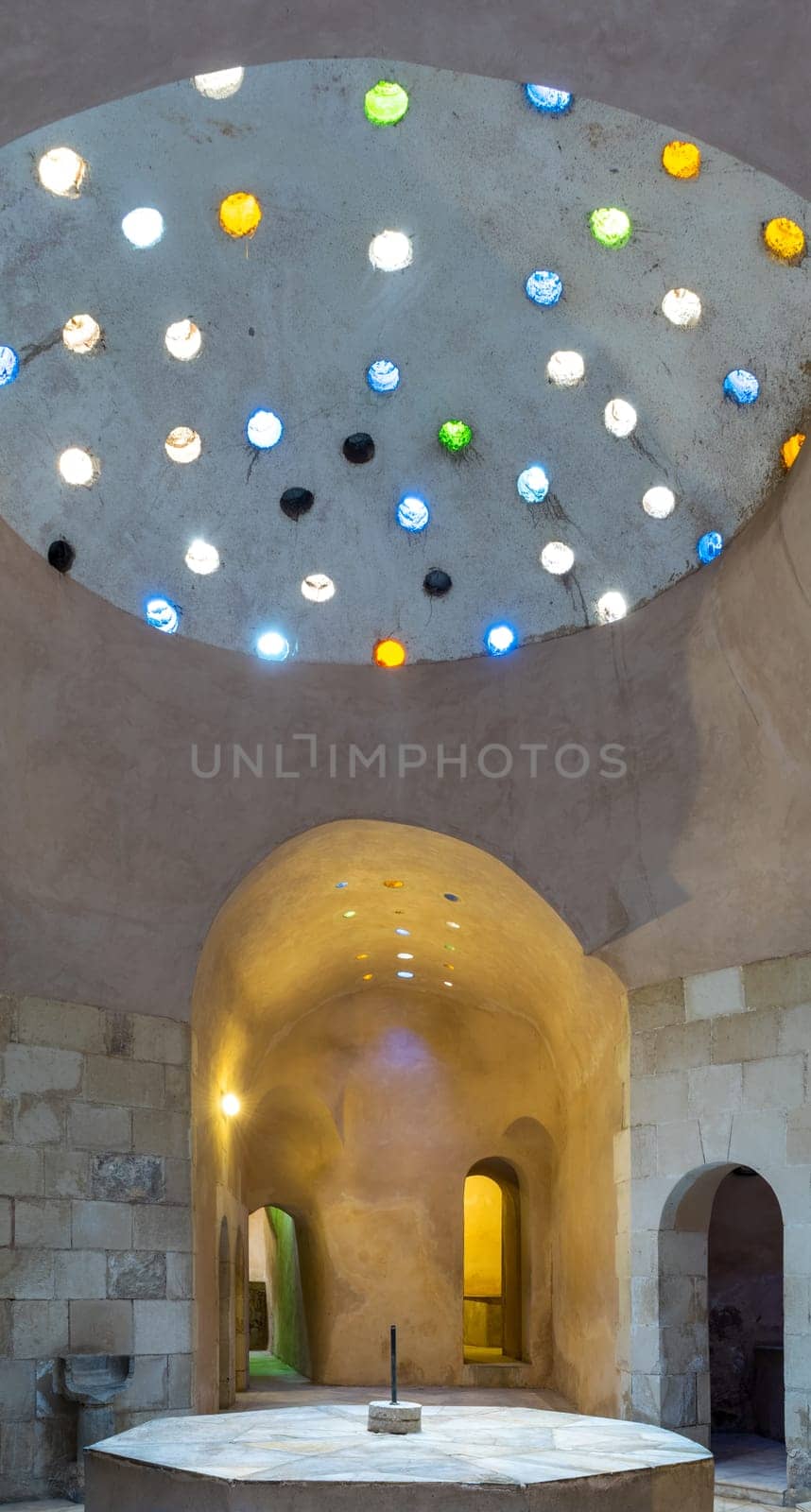 Arched stone wall lighted by colored circular shaped roof holes at a historical traditional Turkish style bath named Hamam Inal, Medieval Cairo, Egypt