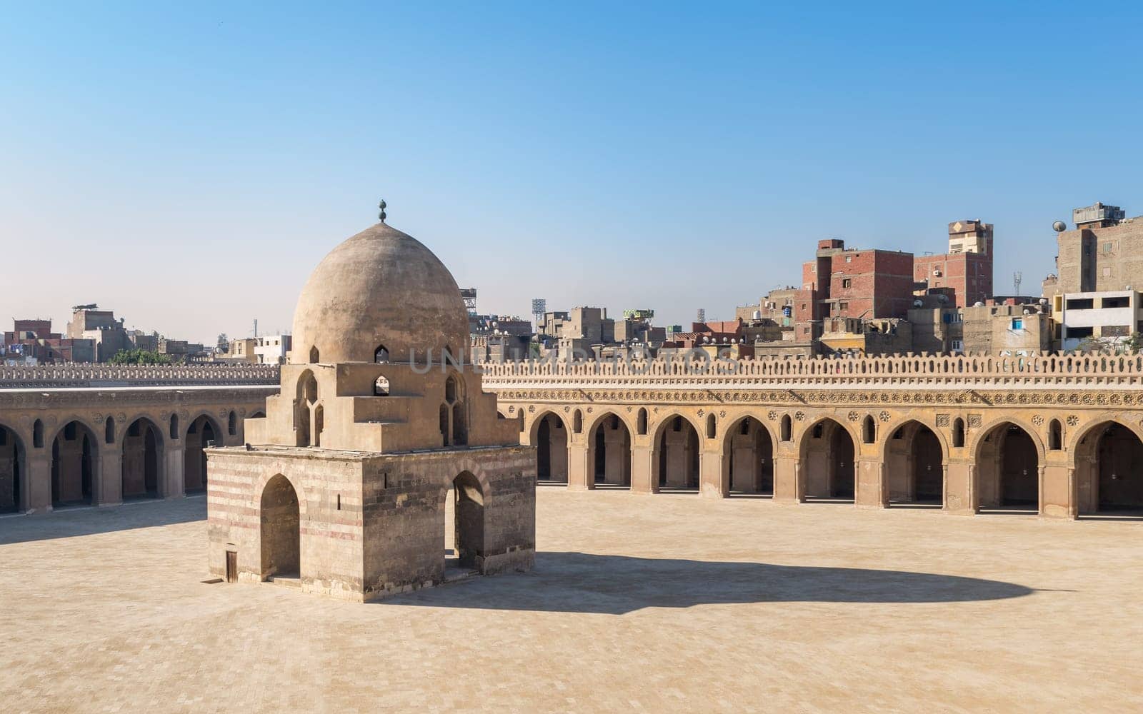Courtyard of Ibn Tulun public historical mosque with ablution fountain and arched passages surrounding the courtyard in the background, Sayyida Zaynab district, Medieval Cairo, Egypt