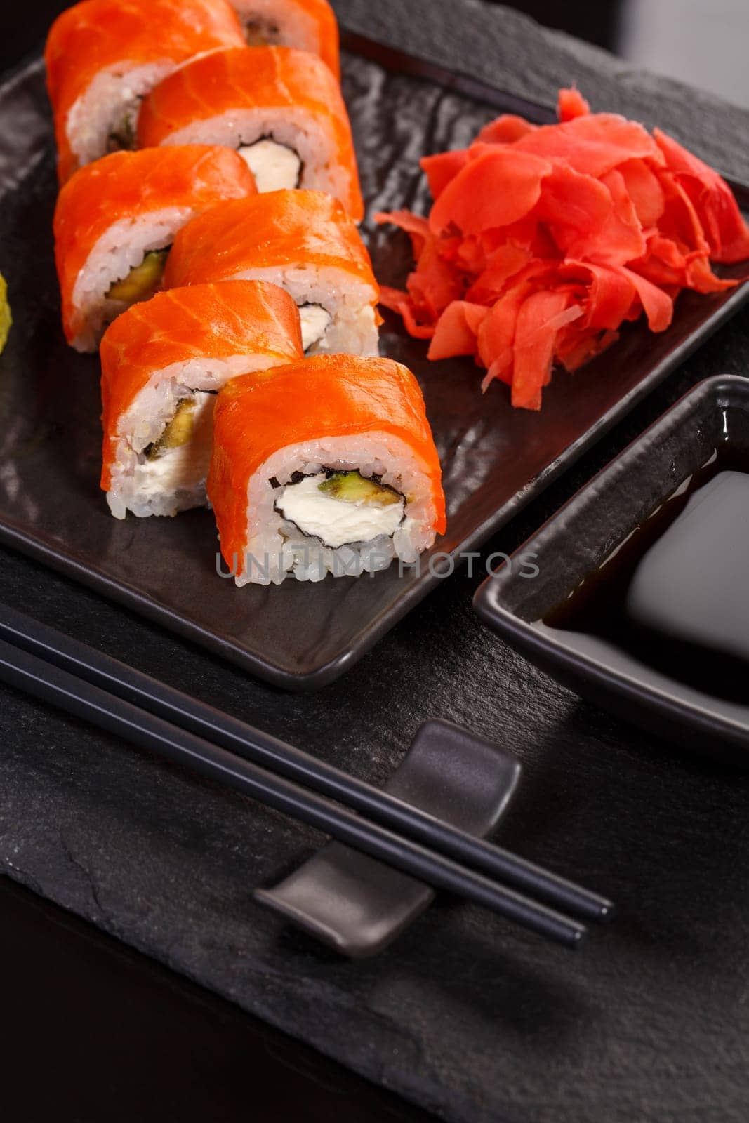 Japanese sushi with soy sauce and chopsticks on black background. Close up.