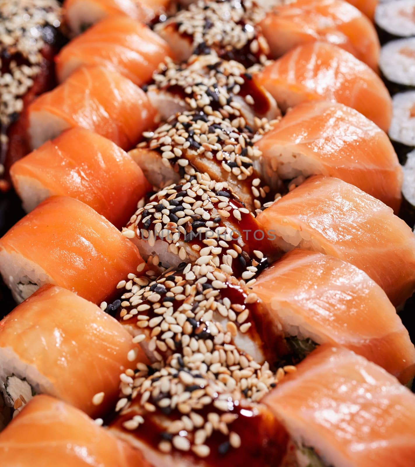 Three rows of sushi rolls with salmon and tuna close up. Concept of delicious traditional Japanese cuisine, delicious seafood and restaurant menu.