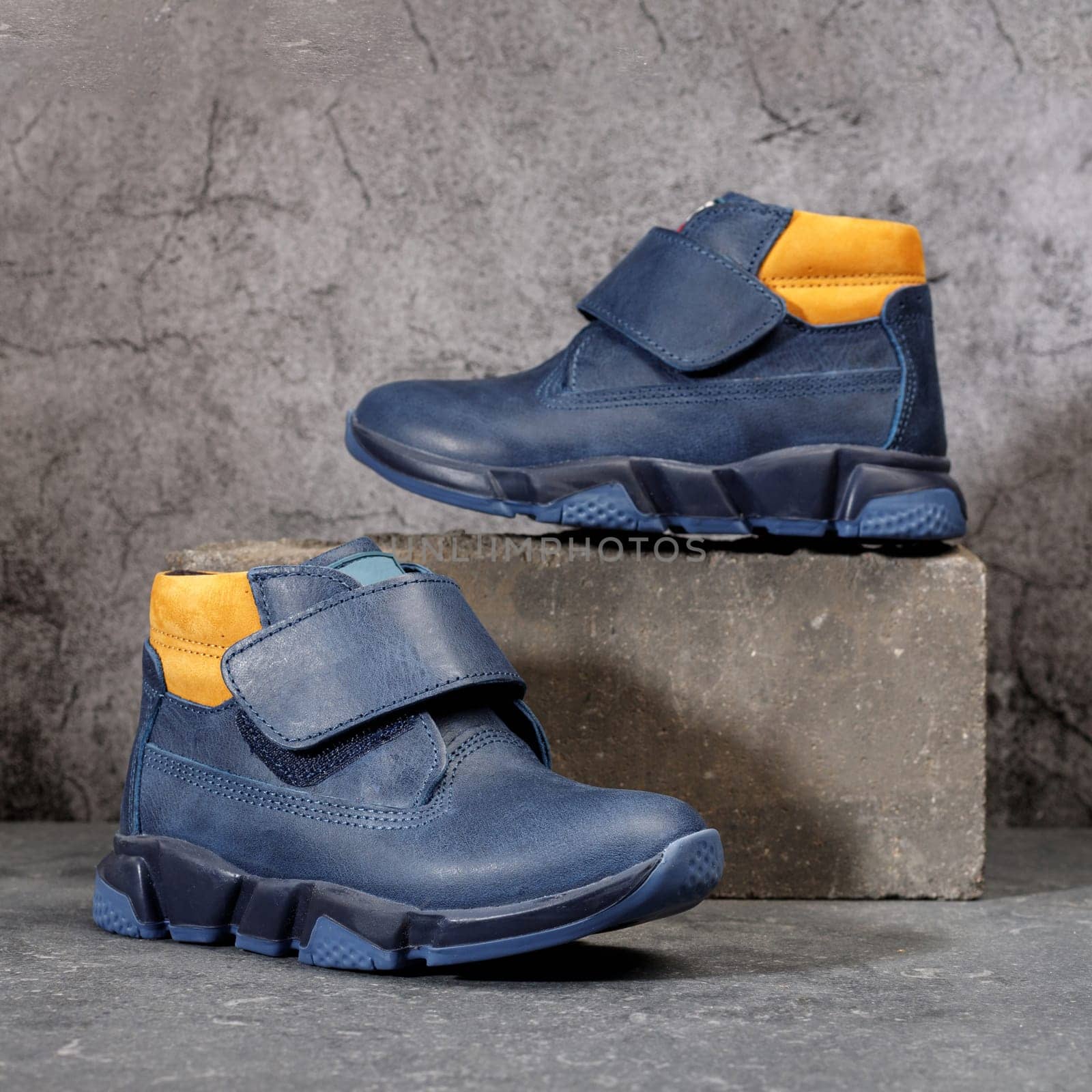 Blue winter sports shoes with orange inserts and velcro for men on a gray concrete background. Boots for the winter and autumn seasons.