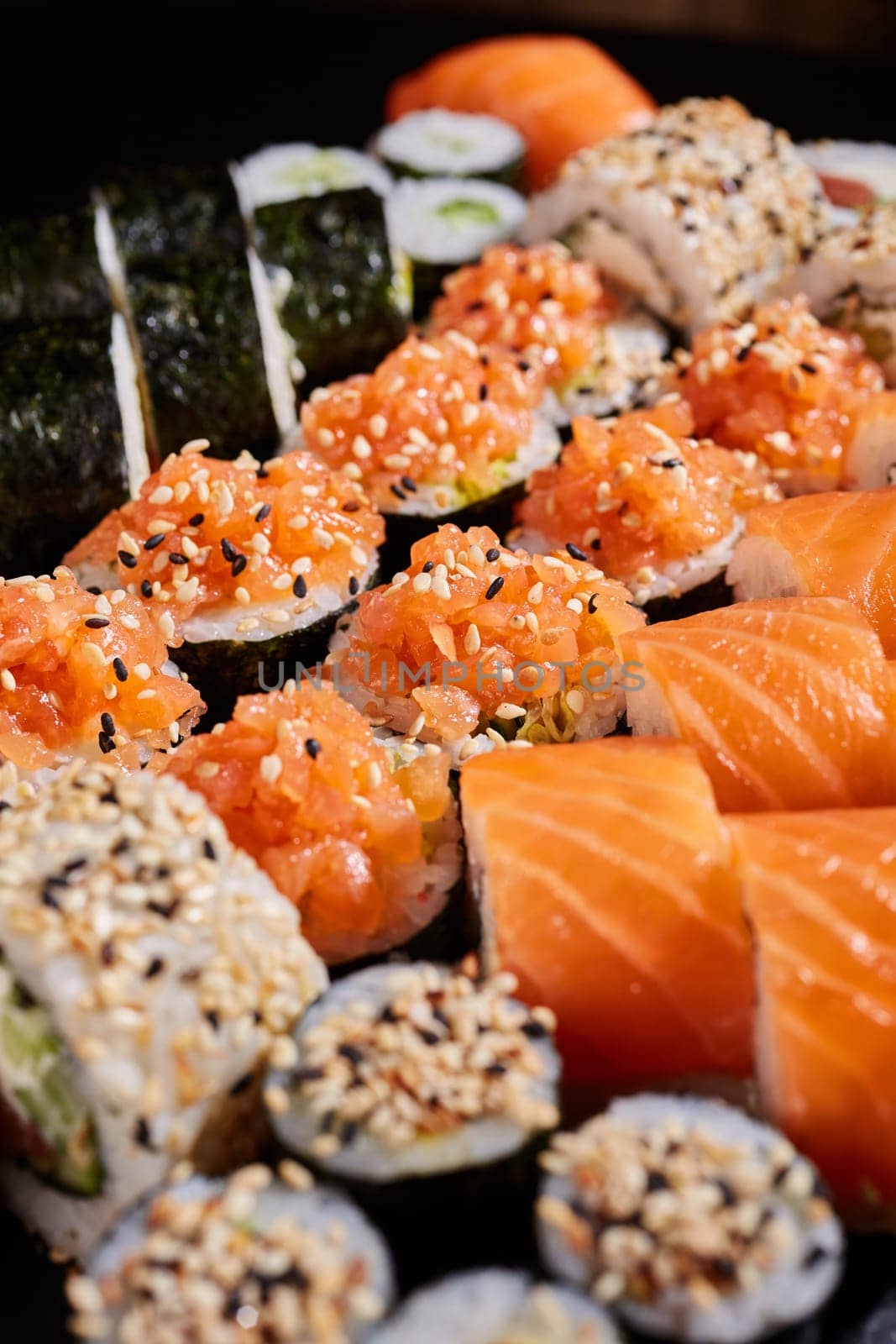 Close up of a set of sushi genera with raw salmon and sesame seeds. Japanese traditional cuisine. Selective focus.