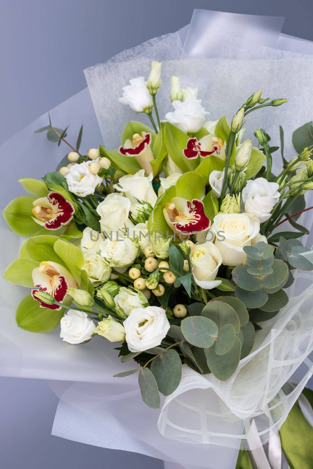 Fresh flowers for any holiday. Close up of a bouquet in green color scheme with roses, eustoma and irises. Concept of floristics and flower arrangements.
