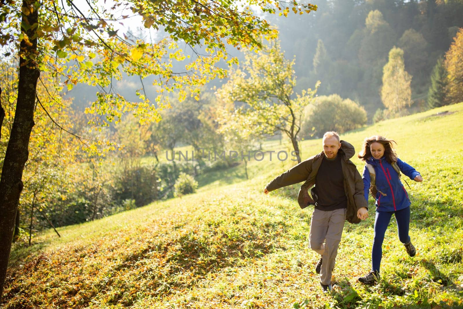 Female and male young active hikers have fun and run in the middle of the mountains. Man and a woman went on a mountain trip. Concept of adventure, travel and tourism.
