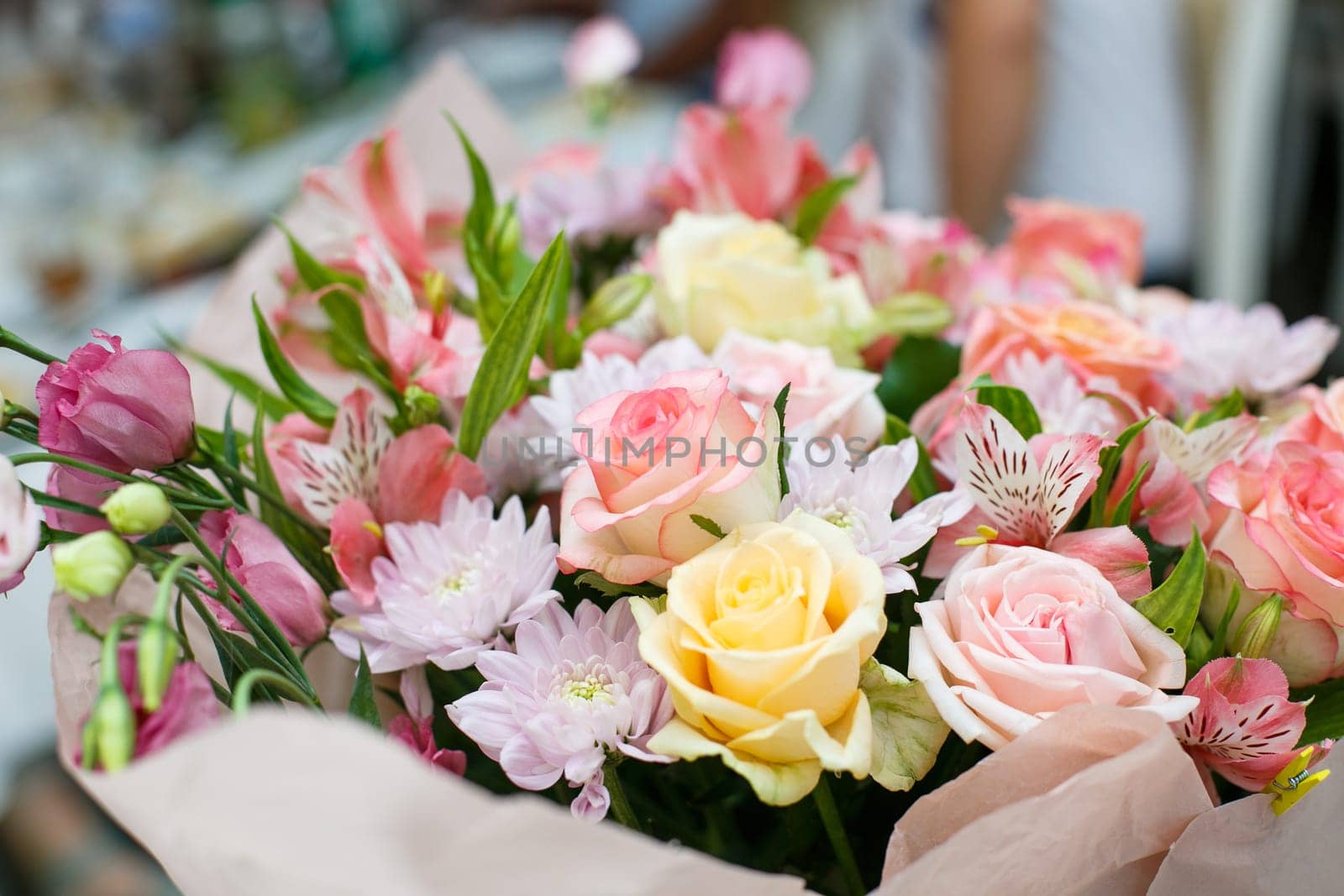 Composition from flowers. Close up of a festive bouquet of fresh flowers made in pink. Roses, astrumeria and chrysanthemums in one bouquet. Concept of giving flowers for a birthday or wedding.