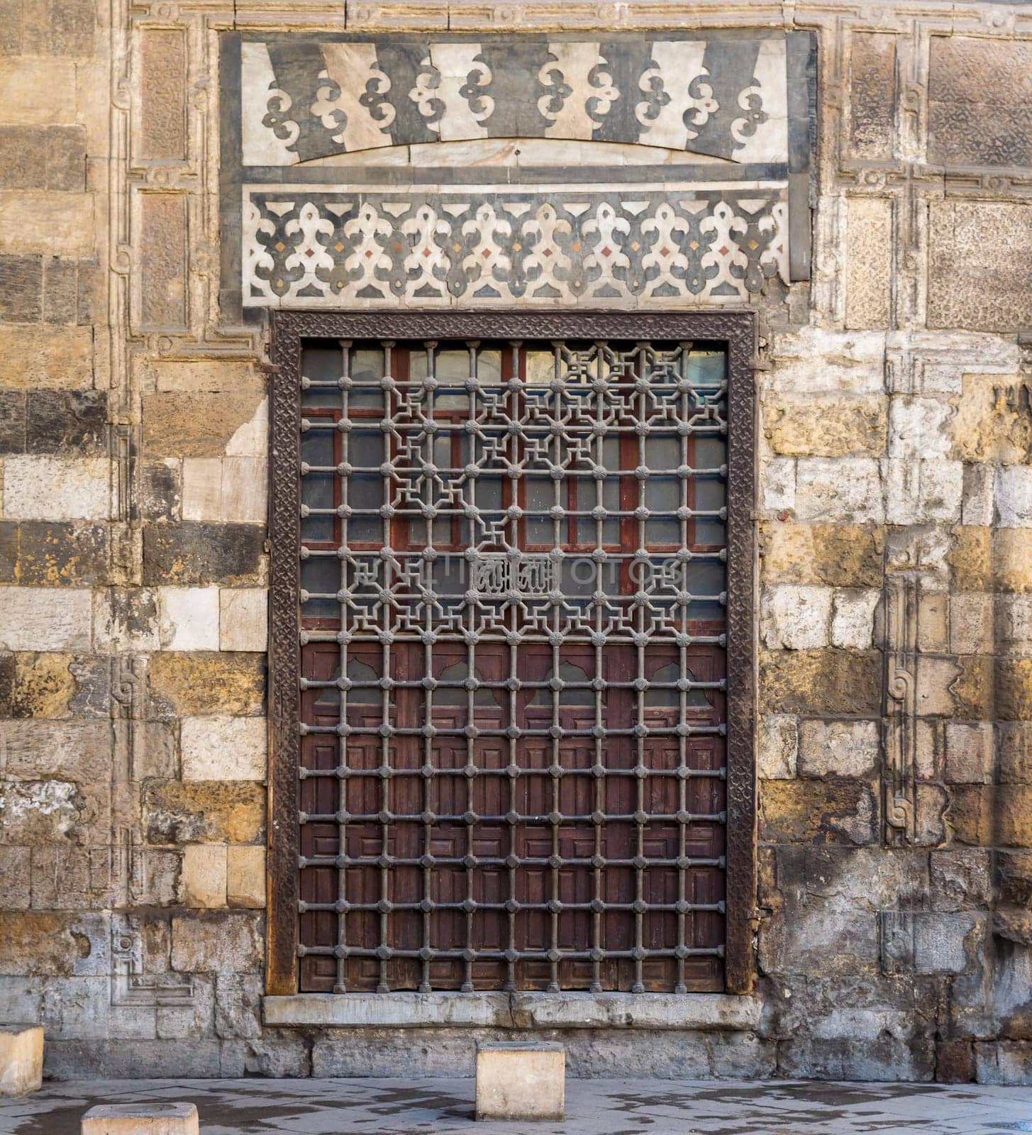 Wooden grunge window with decorated iron grid over stone bricks wall, Moez Street, Cairo, Egypt