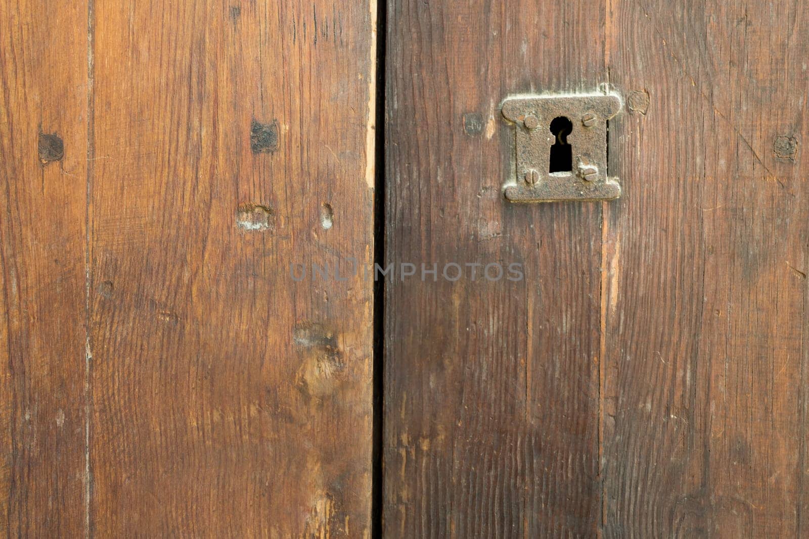 Rusted keyhole over an old weathered wooden grungy door