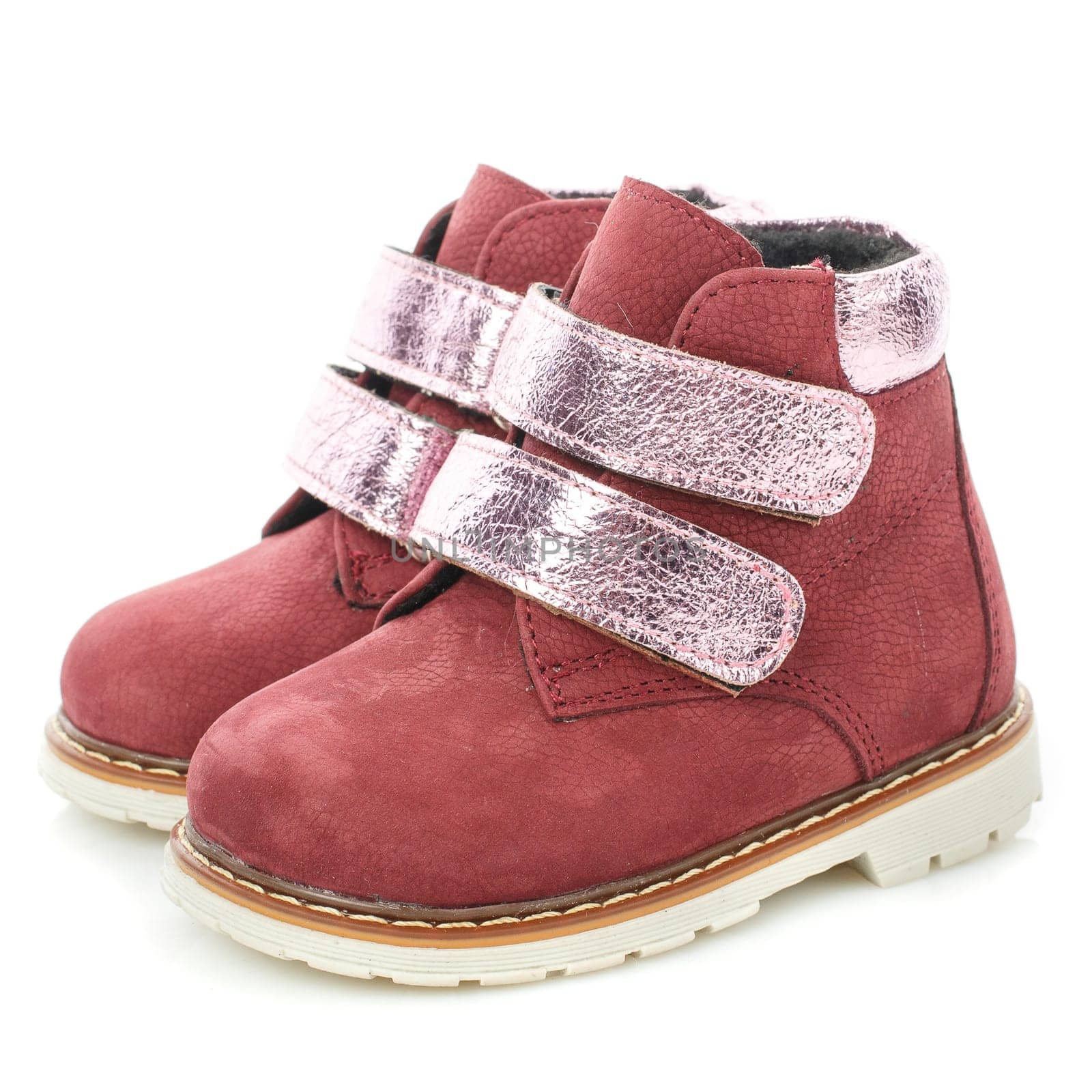 Side view of a pair of leather baby girls red shoes isolated on white background. Warm children's shoes with silver velcro and insulation inside. Children's fashion and style concept.