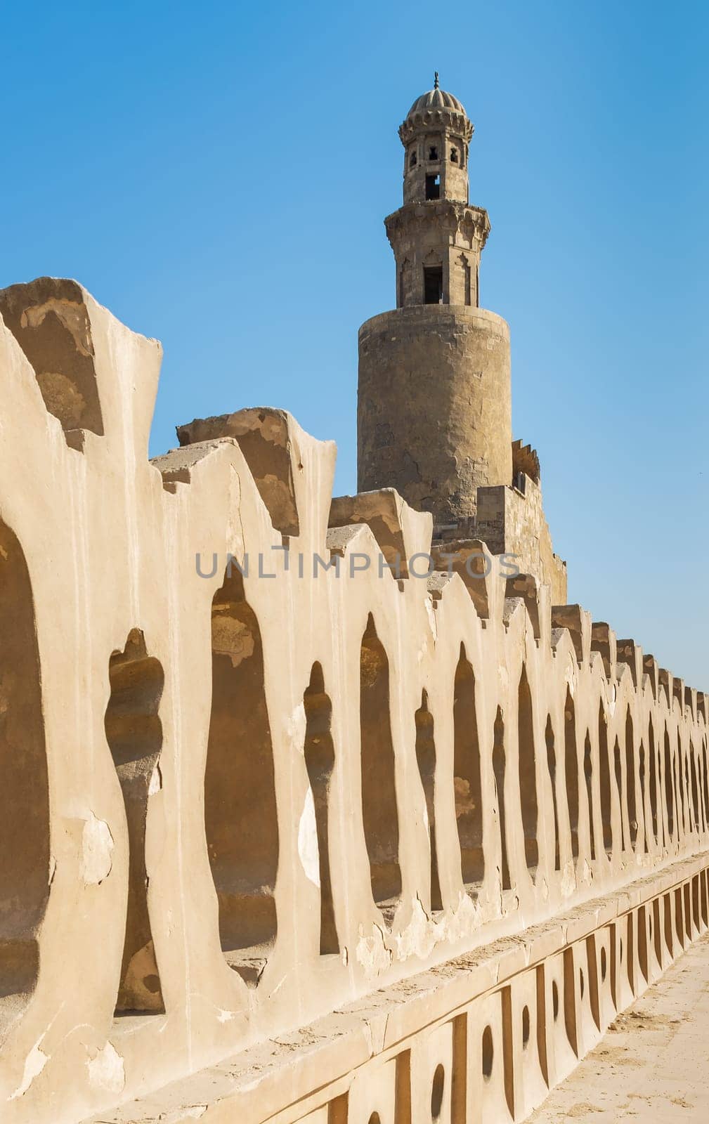 Stone bricks old decorated fence of Mosque of Ibn Tulun revealing minaret of the mosque, Medieval Cairo, Egypt