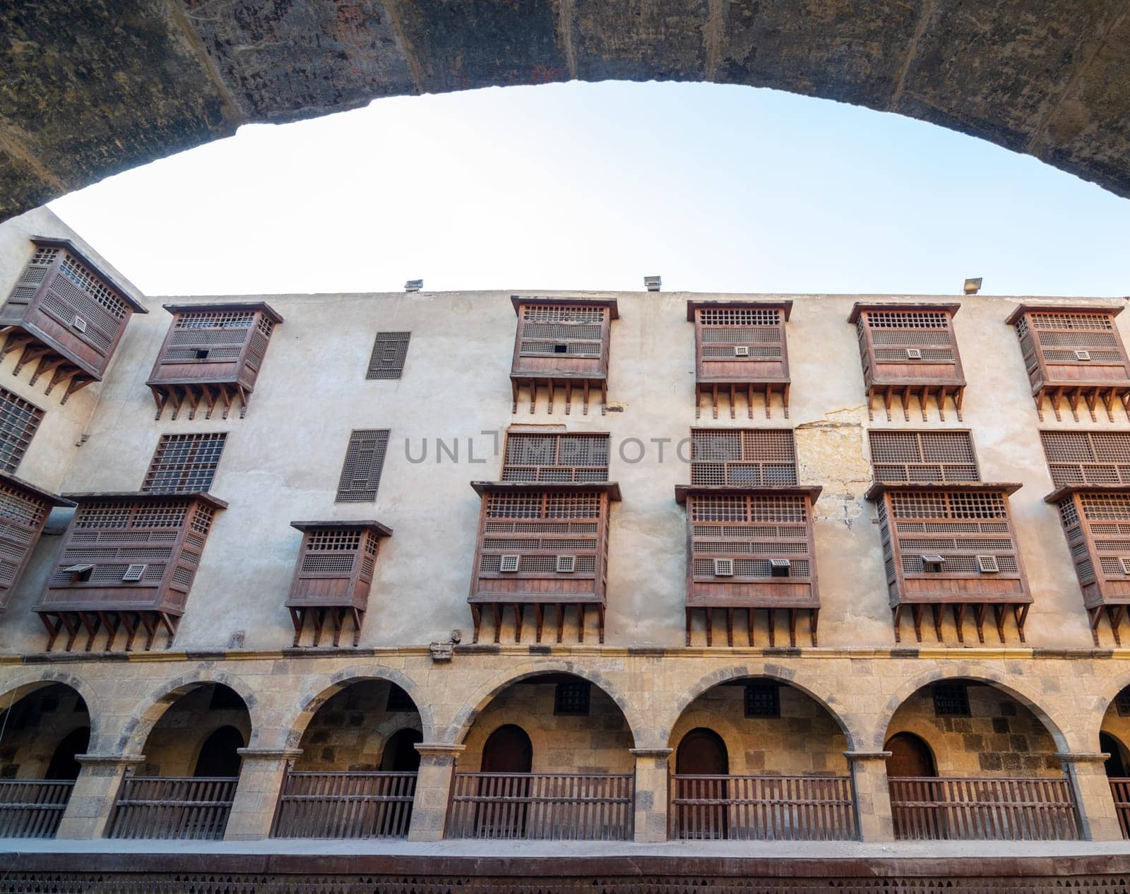 Facade of historic Wikala of Bazaraa building through stone arch , with vaulted arcades and oriental wooden oriel windows, suited in Tombakshia street, Gamalia district, Medieval Cairo, Egypt