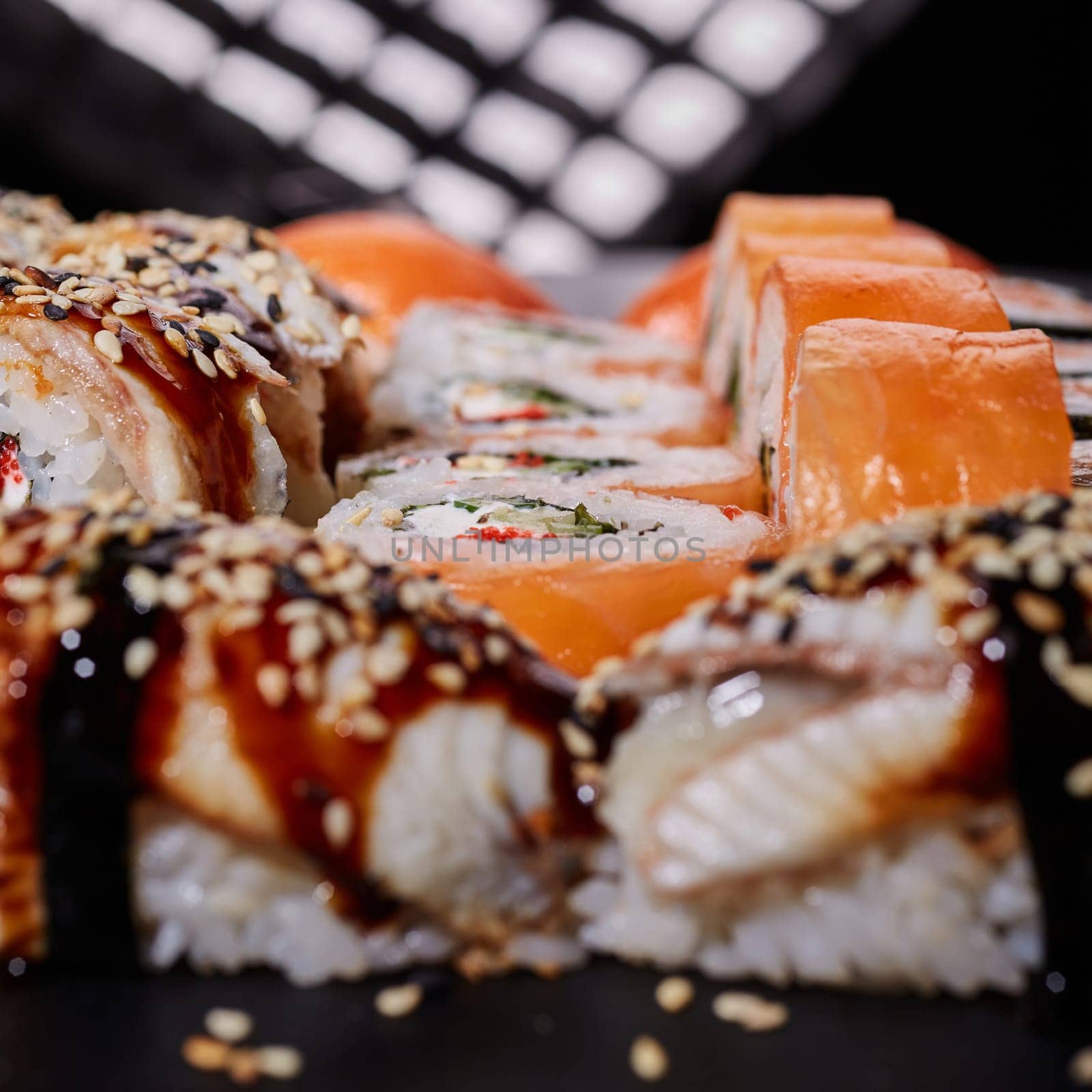 Close up roll of Philadelphia with cream cheese, salmon, cucumber and caviar lies among delicious nigiri sushi. Selective focus. Blurred background.