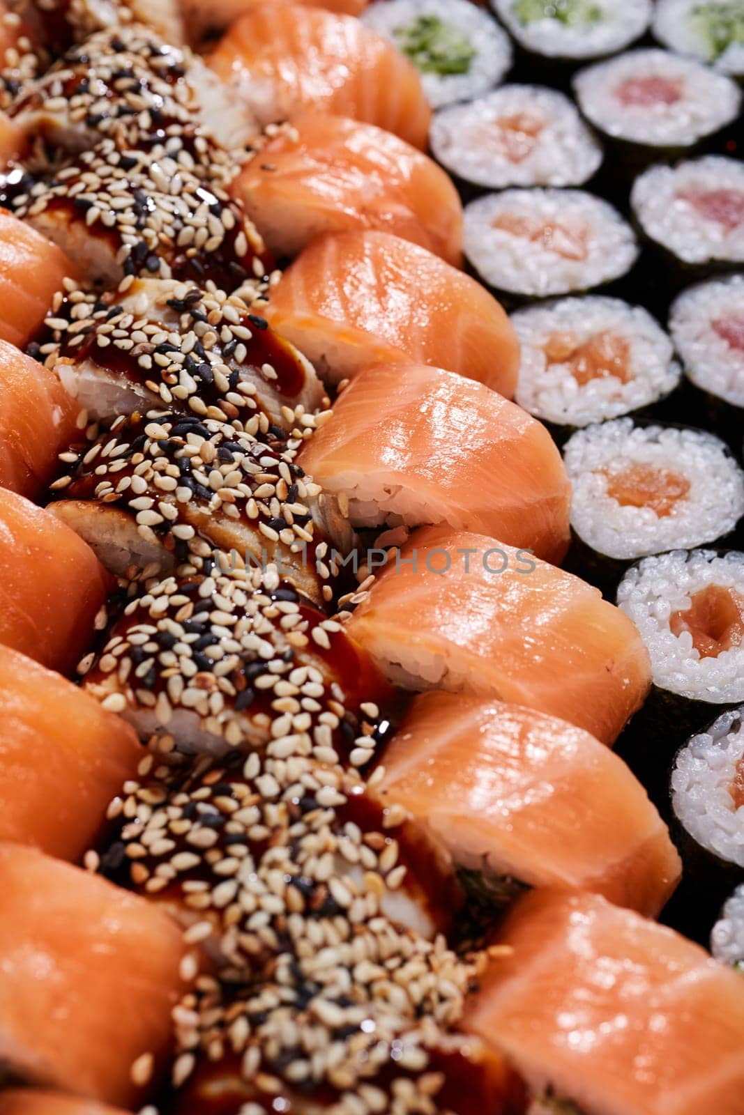 Food background. Large set with rows of different types of sushi rolls with different fillings. Japanese traditional cuisine.