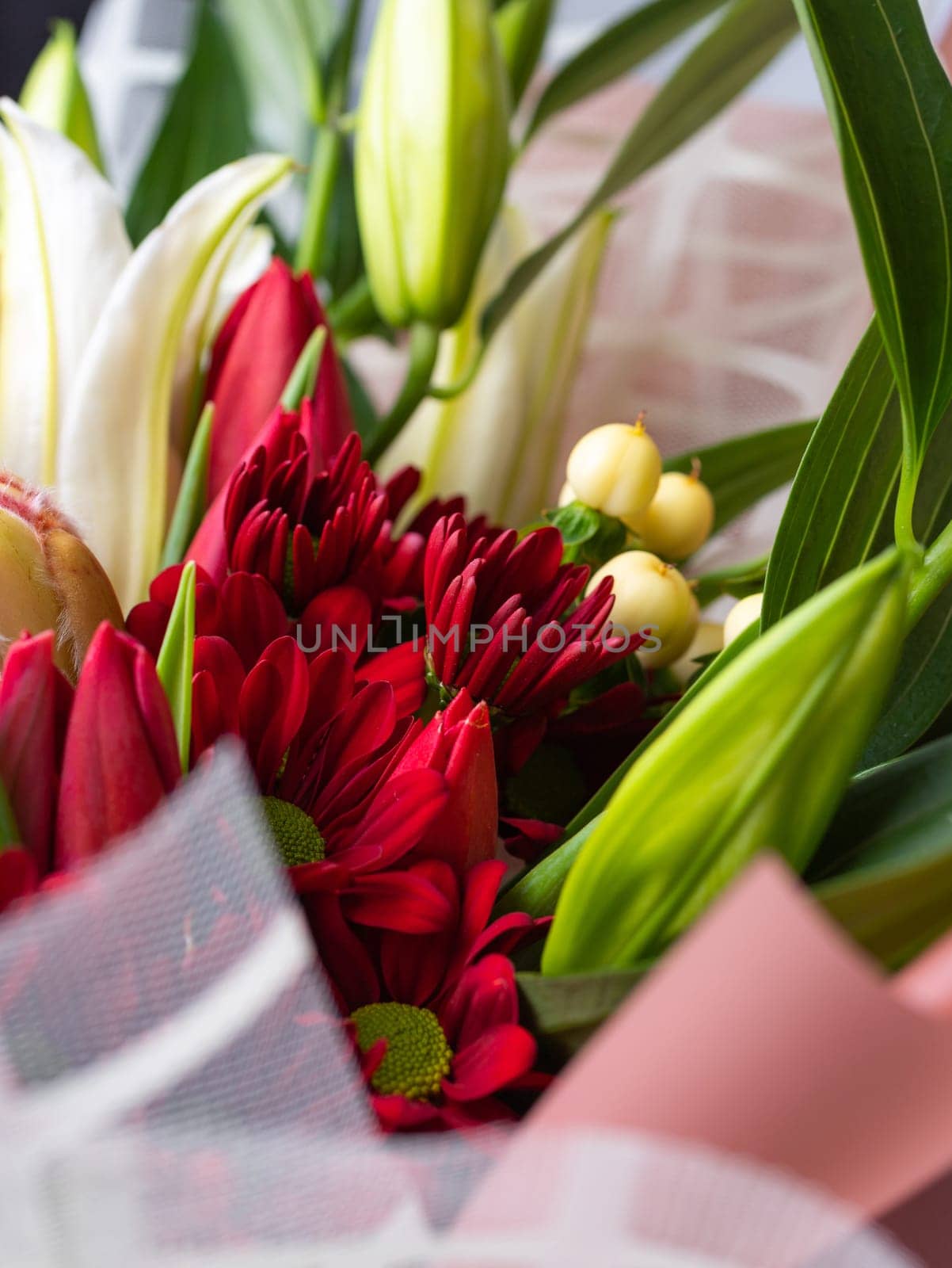 Close up of red chrysanthemums in a festive bouquet among white lilies. Concept of love, International Women's Day, Mother's Day and Birthday. Selective focus.