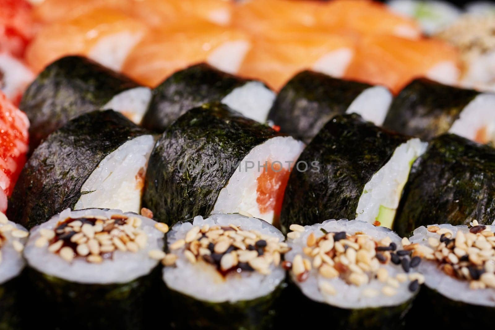 Close up of roll with salmon and sesame seeds wrapped in nori leaves. Japanese oriental cuisine.