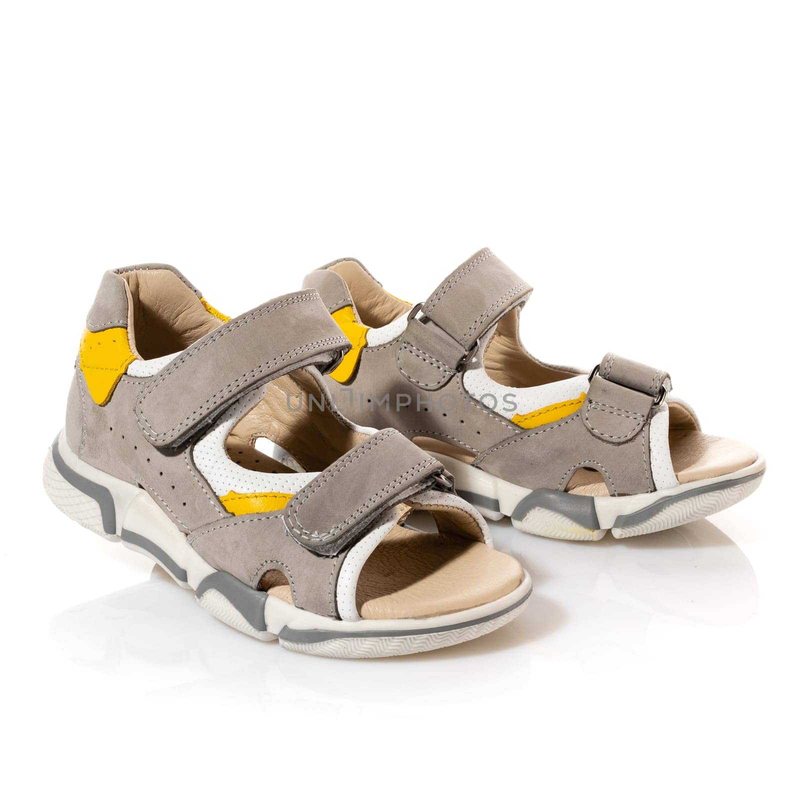 Pair of children's comfortable sports sandals isolated on white background. Close up of beige velcro shoes for little boys. Concept of comfortable walk and shoe sales.