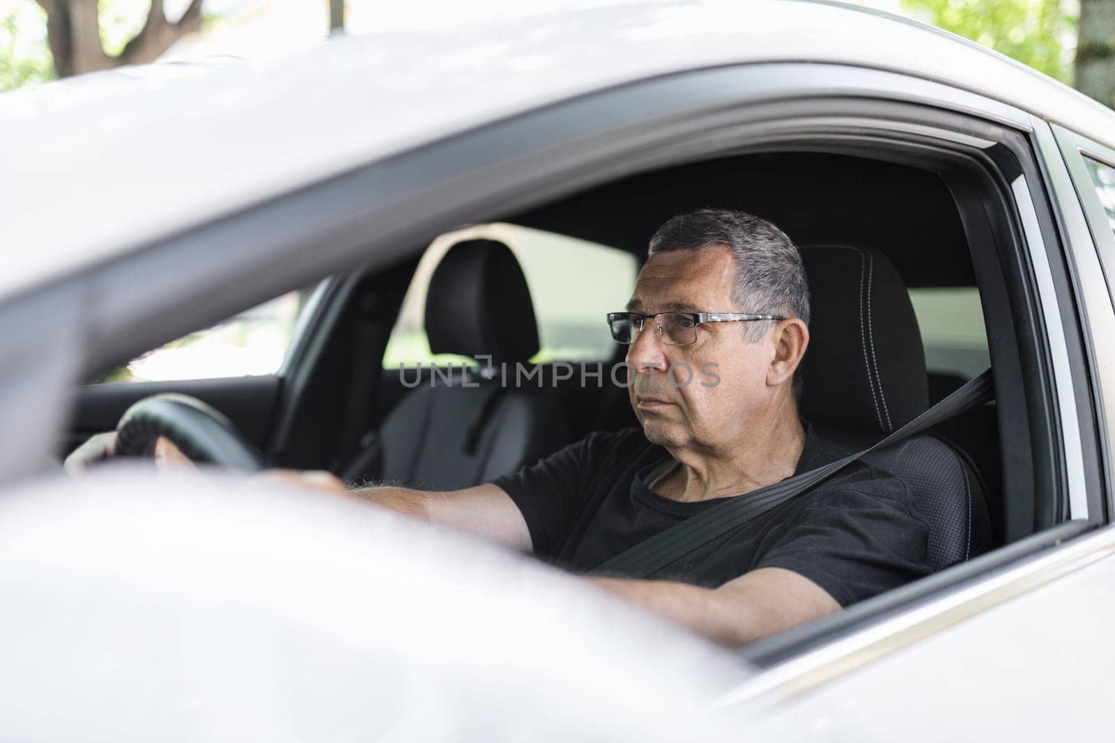 Happy senior in his 70s driving a car