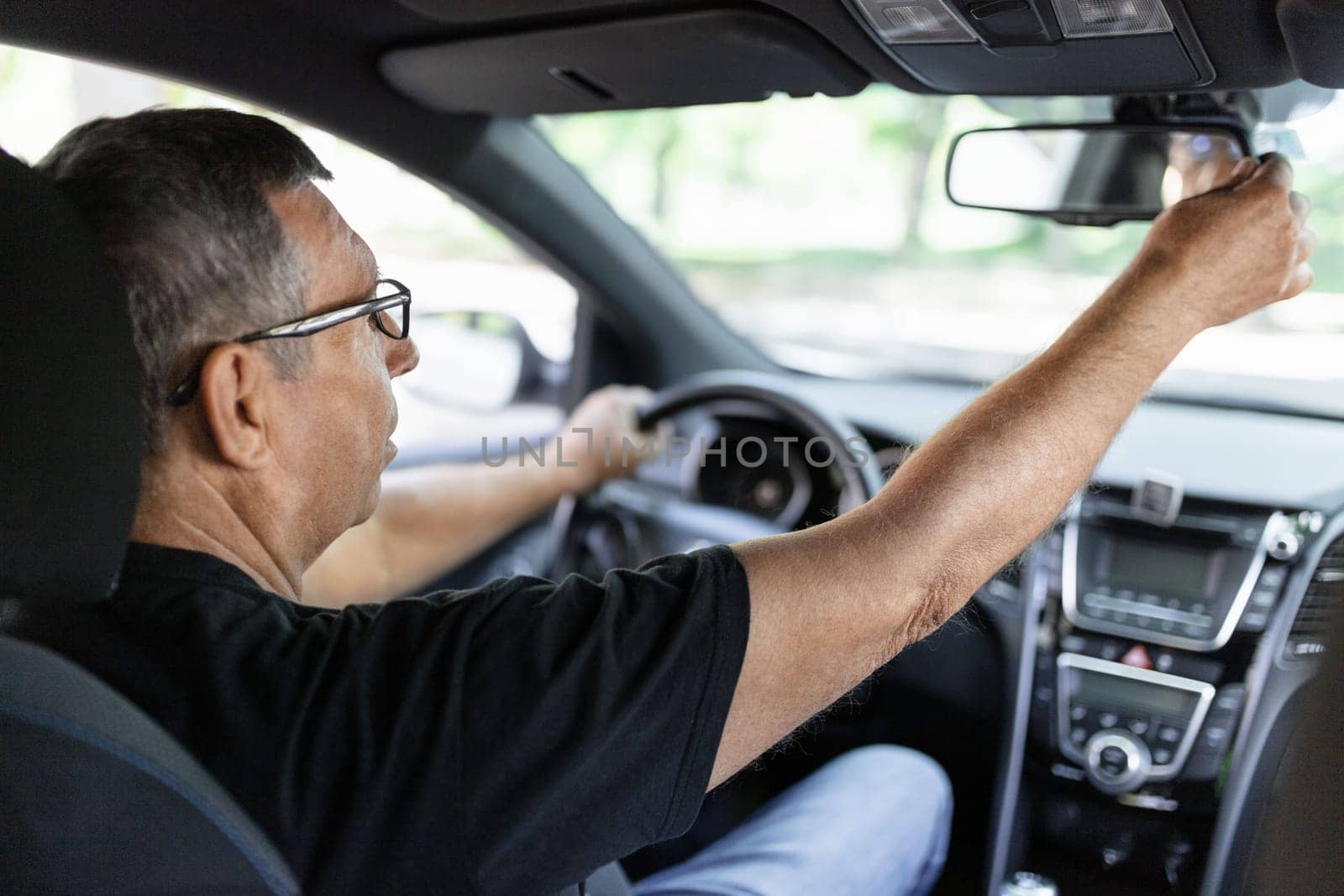 Happy senior in his 70s driving a car