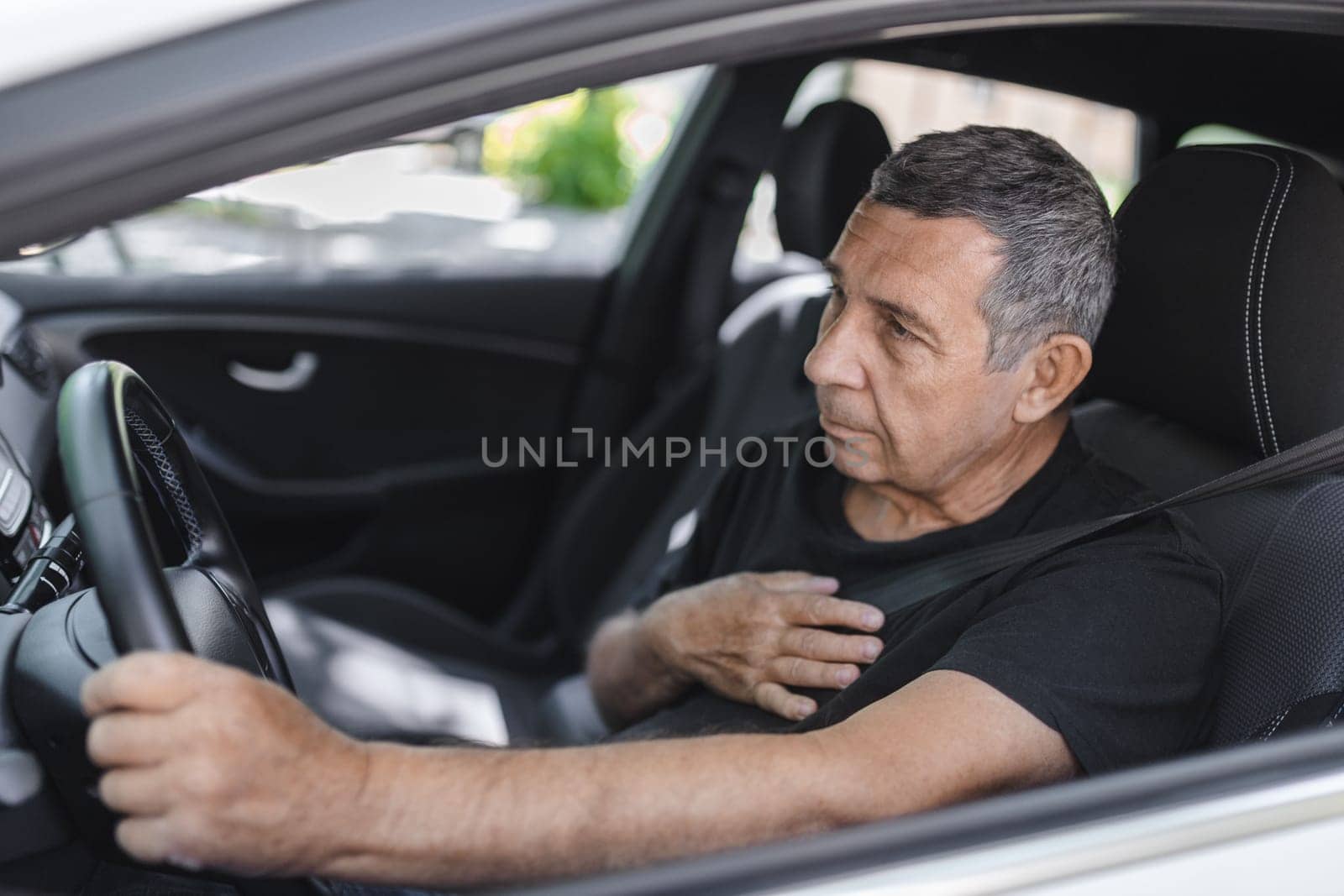 Senior in his 70s, behind the steering wheel with chest pain