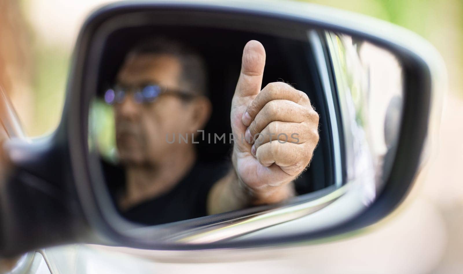 Happy senior in his 70s driving a car