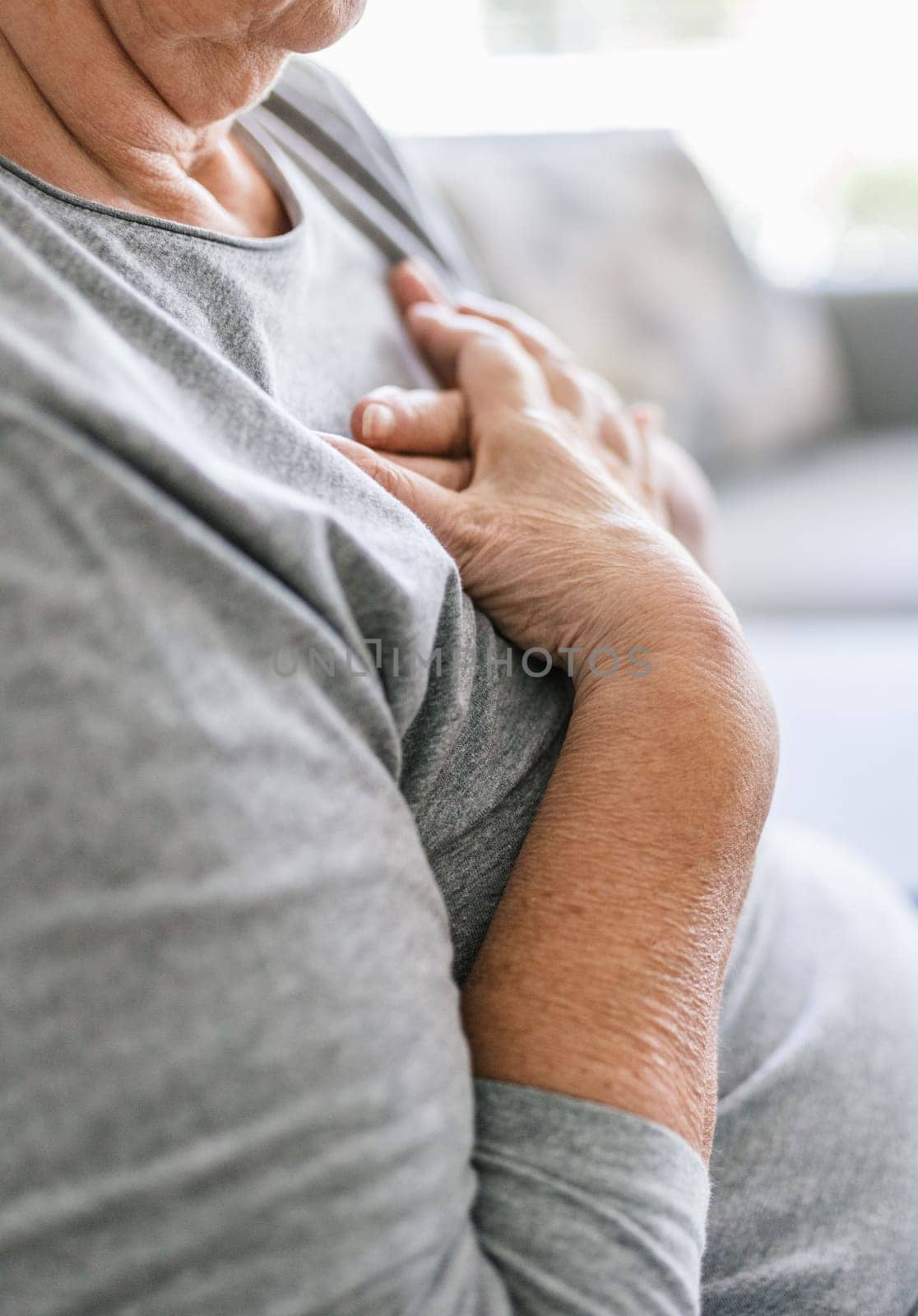 Elderly woman at home with heart pain holding her chest