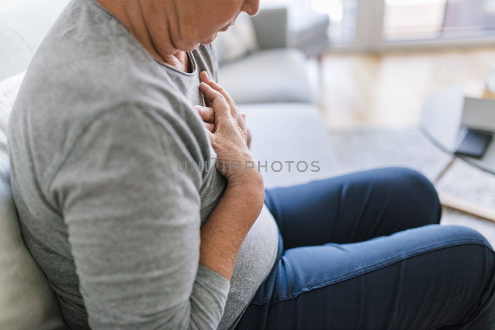 Elderly woman at home with heart pain holding her chest