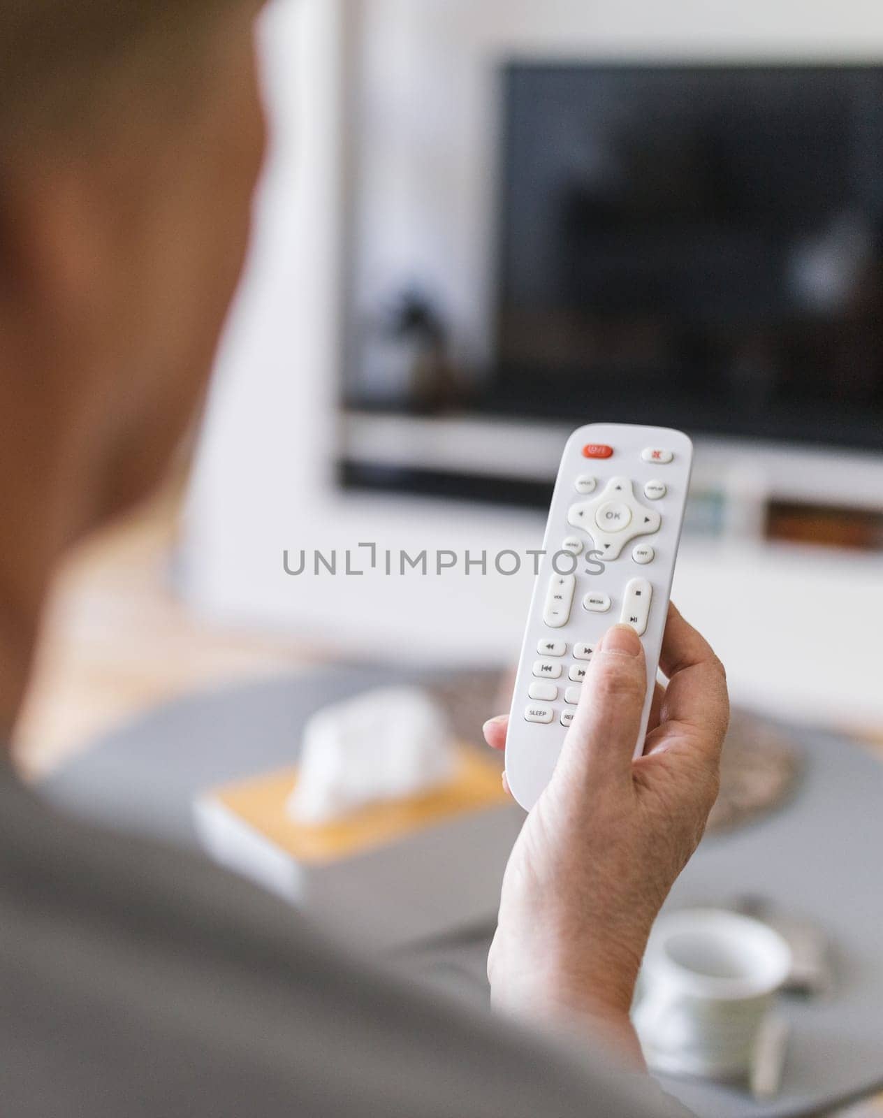 Senior woman with remote control watching television