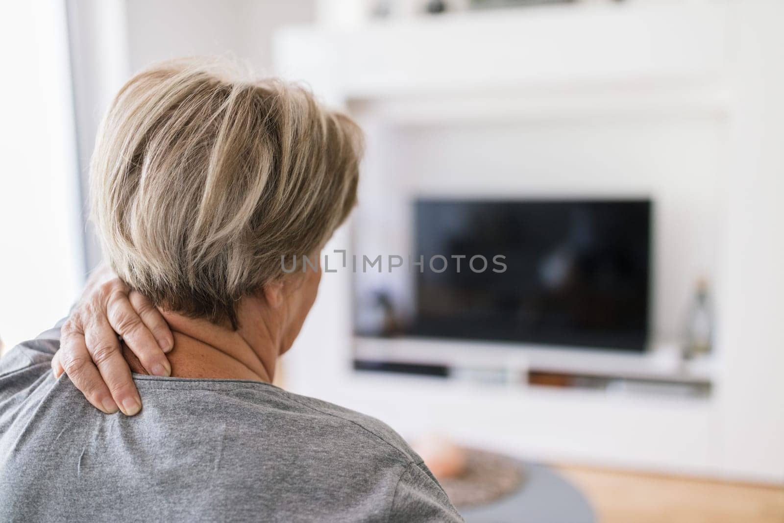 Senior woman in the living room with neck pain