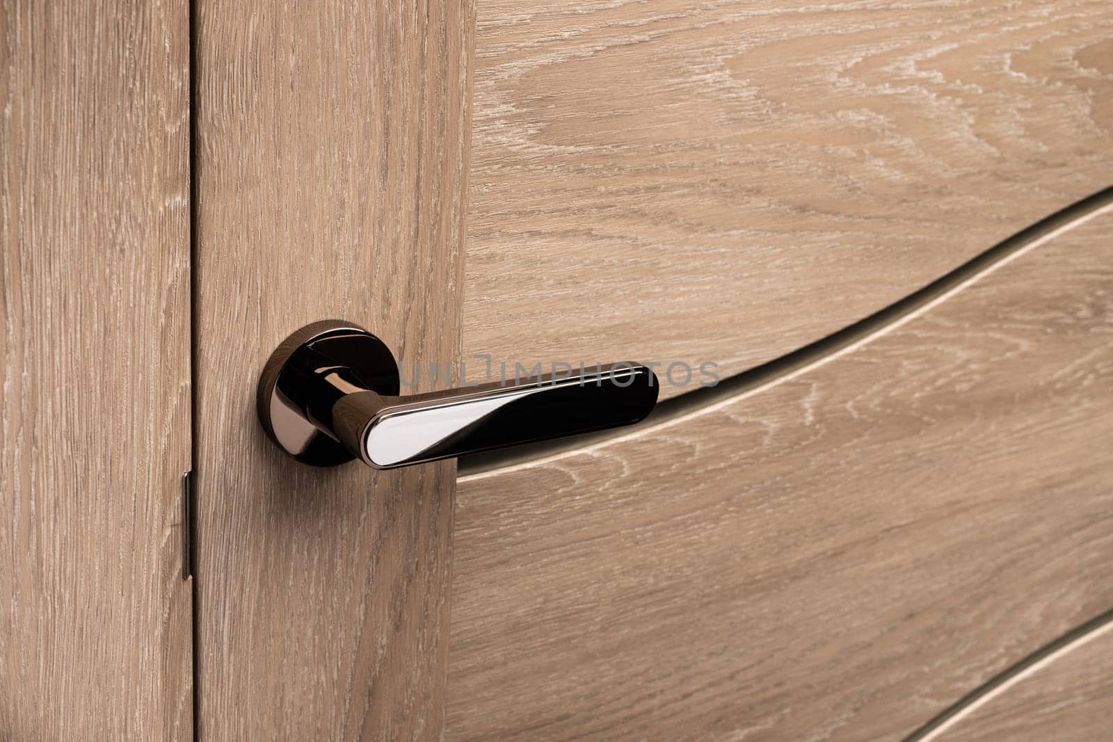 External door handle without protective lock on wooden frame. Close up of metallic door handle on brown front or interior door. Home door design choice concept.