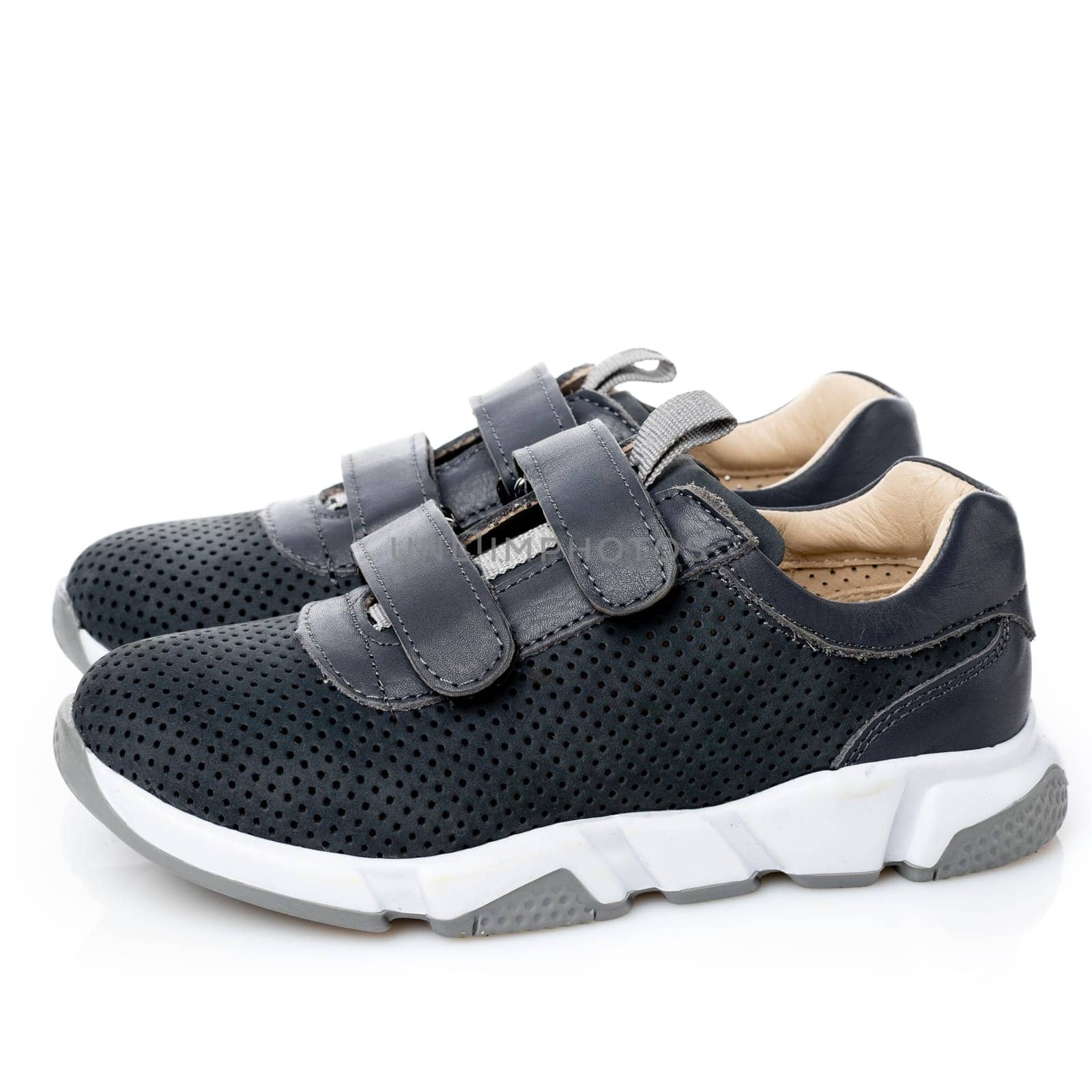 Pair of small sports shoes for boys isolated on white background. Side view of black children's sneakers with velcro and white sole. Concept of comfortable shoes for children.