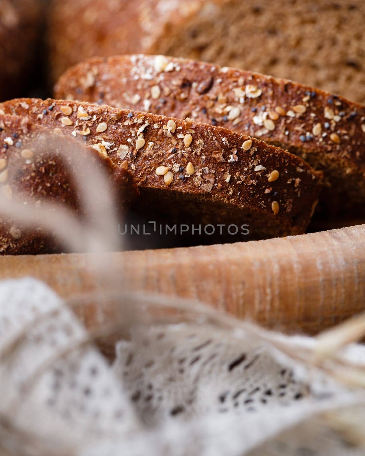 Slices of fresh wholemeal bread with baked crust and various cereals. Close up of homemade bread with sesame seeds lying in clay bowl. Bakery concept. Food background. Selective focus.