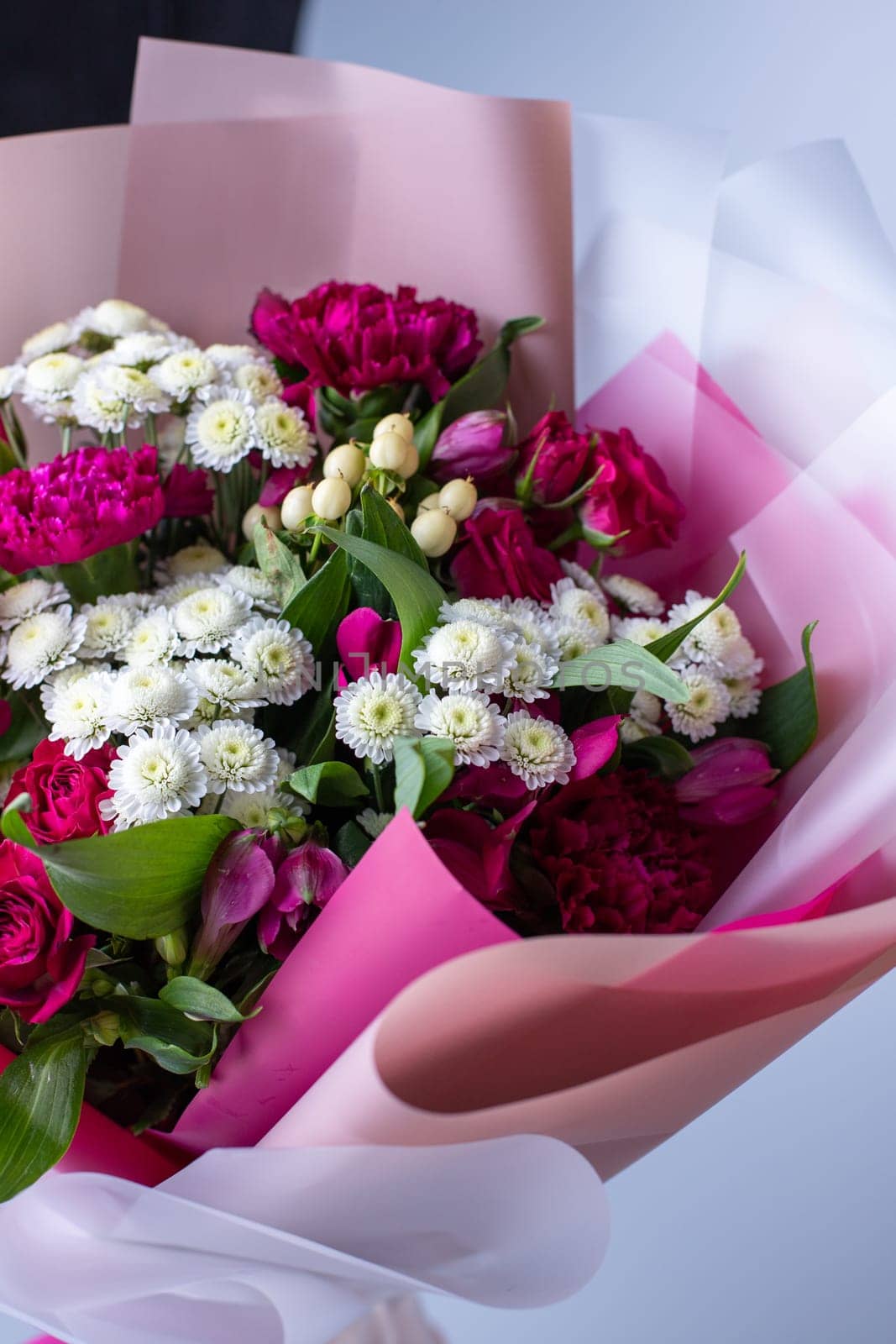 Close up of a bouquet of pink and white flowers wrapped in floral tracing paper. Concept of floristics and composing greeting bouquets. Floral banner.