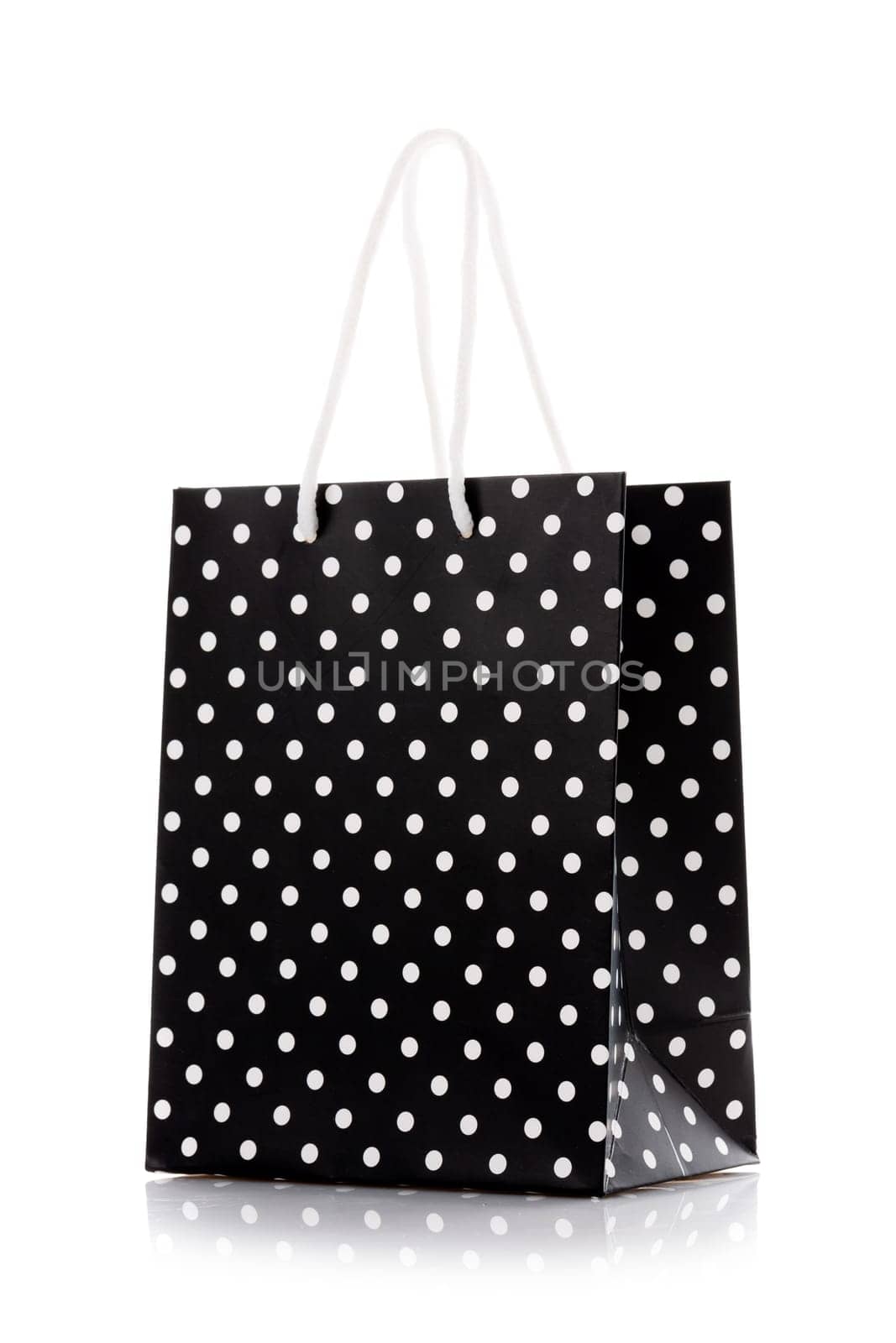 Shopping bag. Black package for shopping or gifts with white handles and dots. Concept of gifts for birthday, women's day, mother's day. Isolated on white.