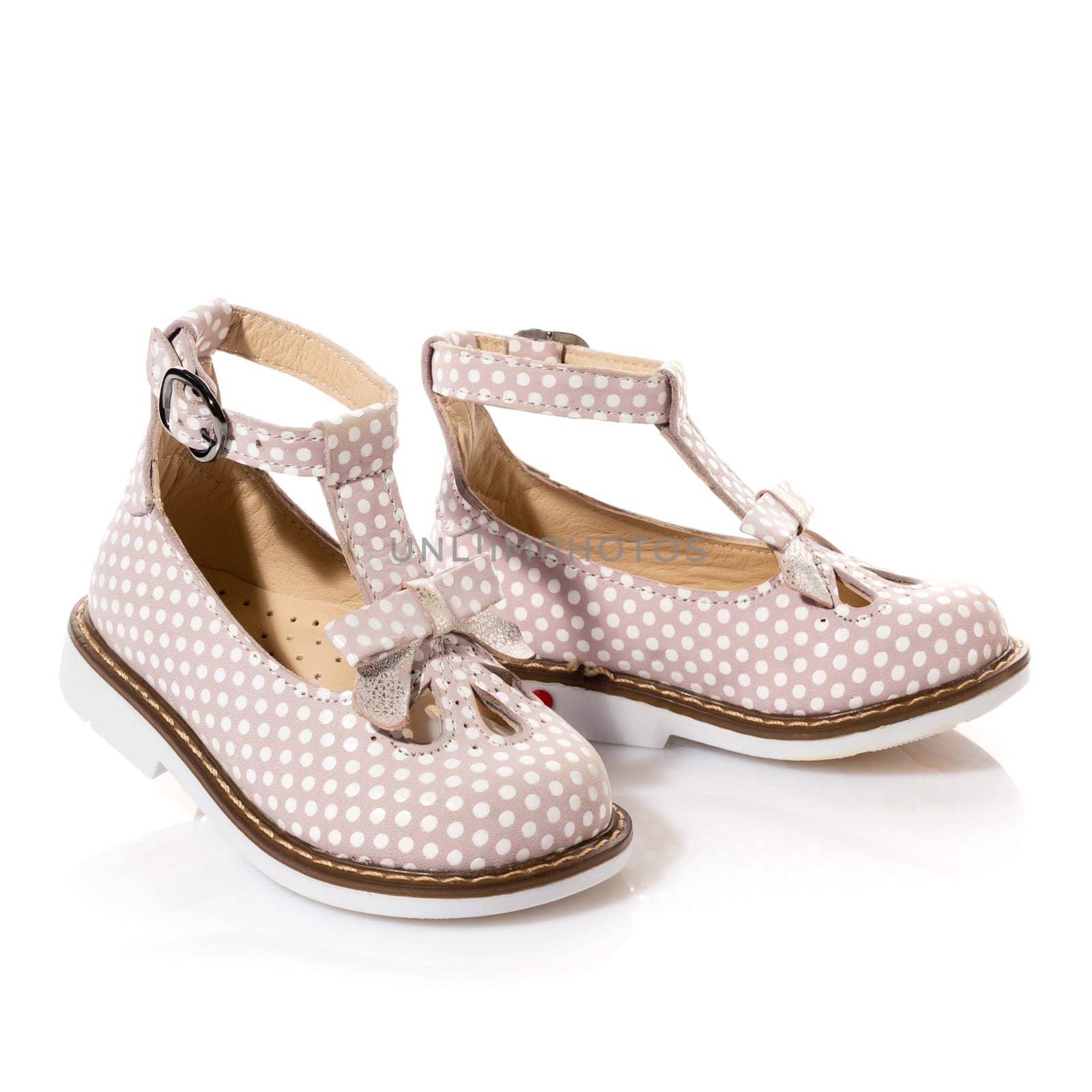 Pair of stylish elegant sandals for little girl isolated on white background. Pink shoes with white dots and bow. Children's fashion concept. Copy space.